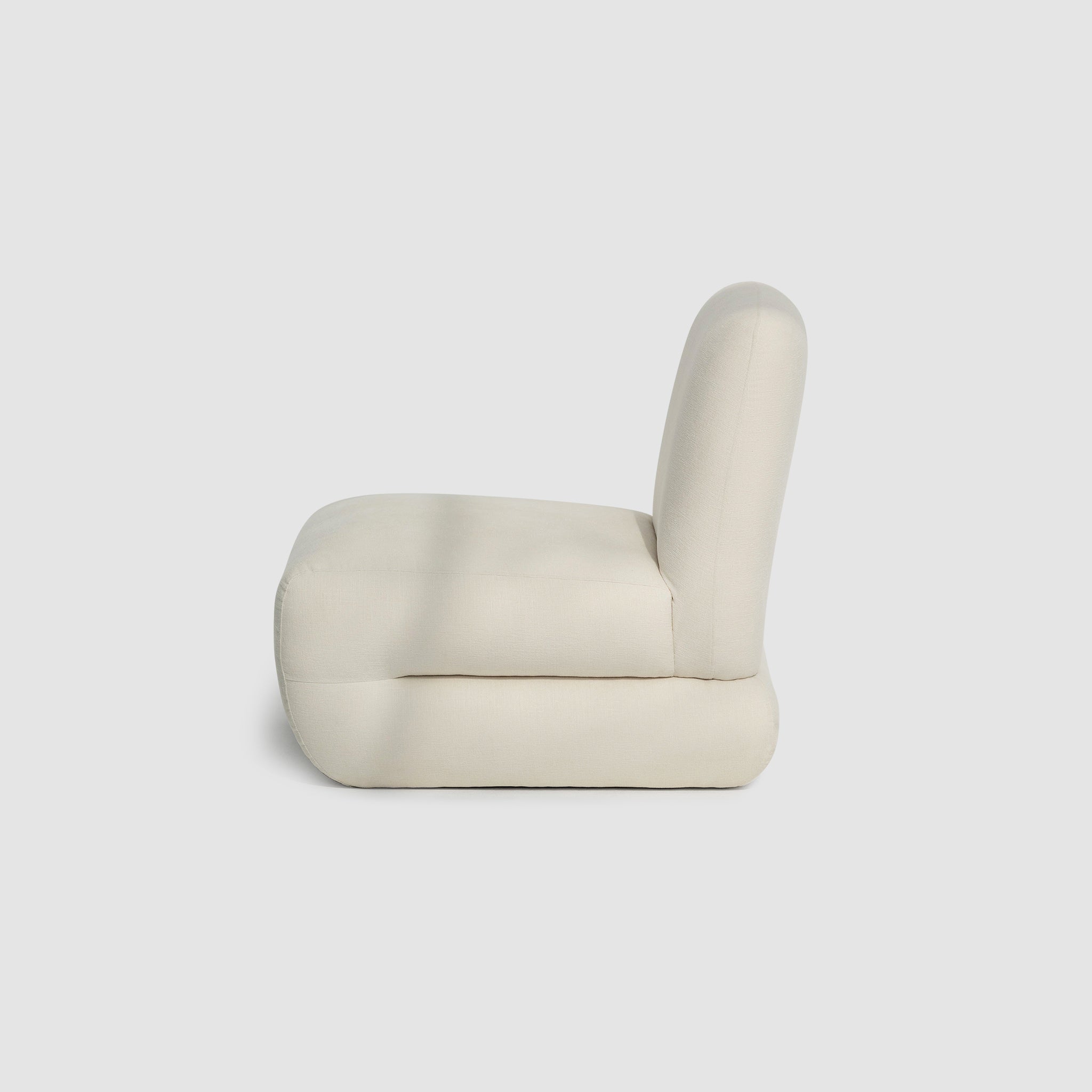Side view of The Bopie Accent Chair in a soft, cream-colored fabric, highlighting its plush and modern design. Modern leather accent chair.