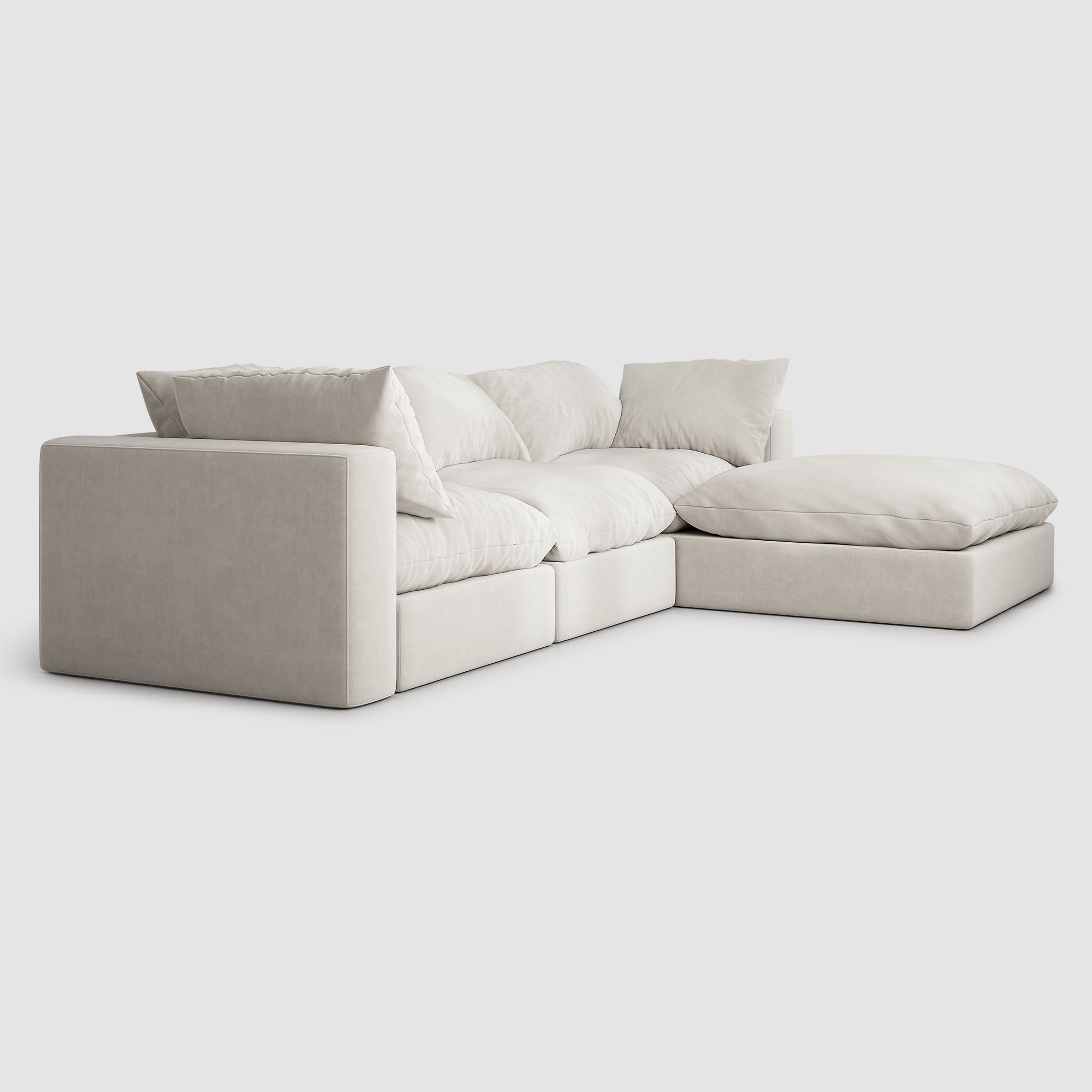 White sectional couch with detachable ottoman in a modern living room. The couch has a solid wood frame and is upholstered in white fabric. The removable cushions are filled with a premium blend of foam and feathers, providing unparalleled softness and support.