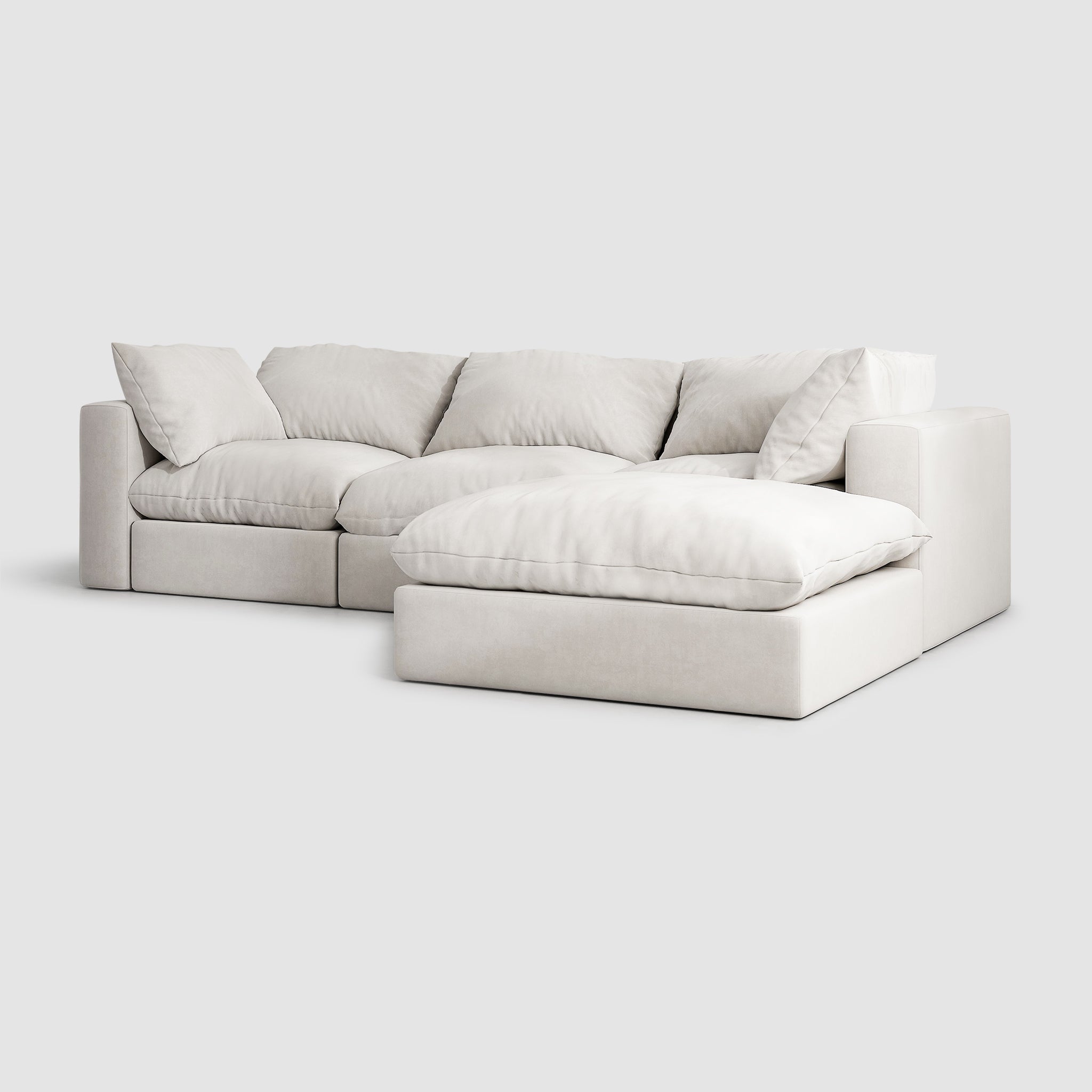 White sectional couch with detachable ottoman in a modern living room. The couch has a solid wood frame and is upholstered in white fabric with removable covers. This luxurious couch is perfect for relaxing in style.