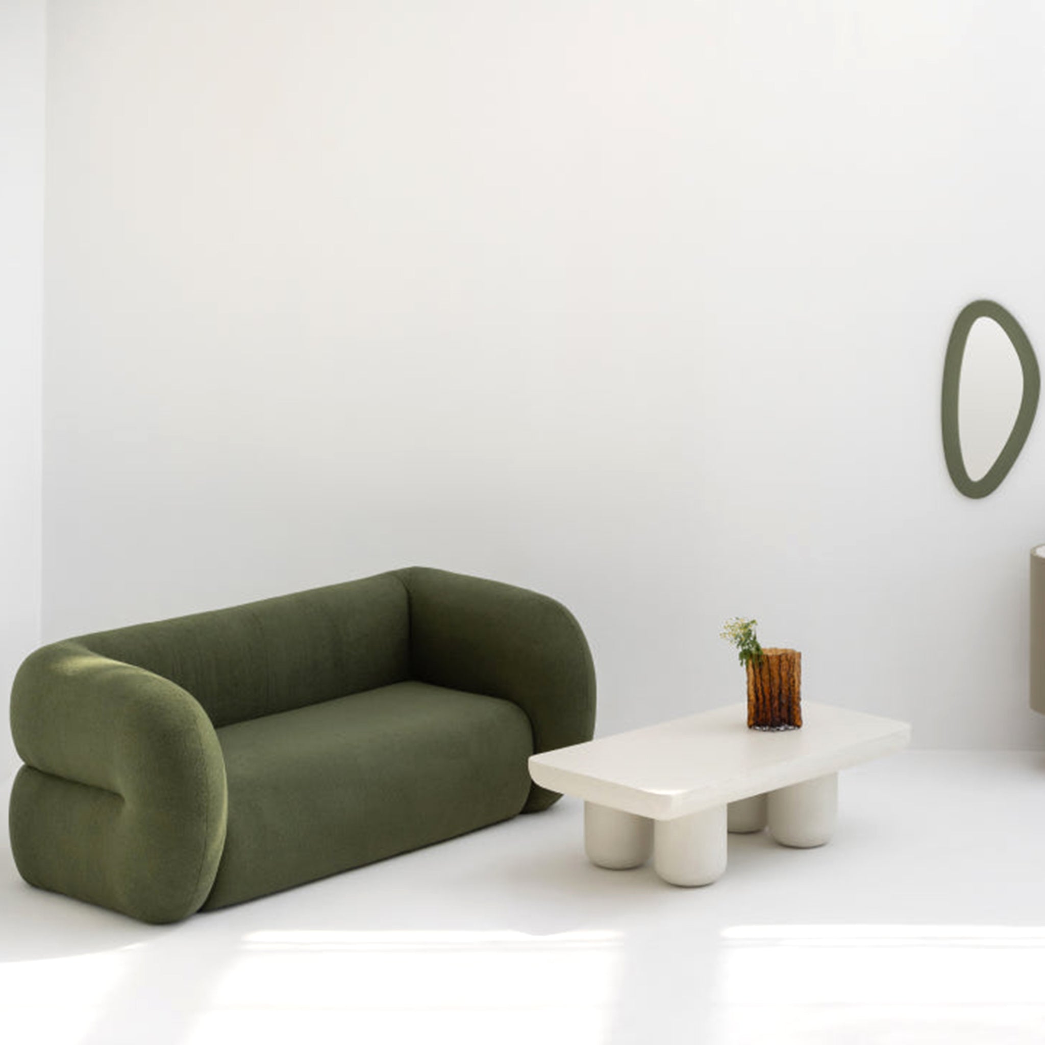 Modern minimalist living room featuring a stylish green sofa and a unique white coffee table with rounded legs, complemented by a contemporary wall mirror and a small decorative vase.