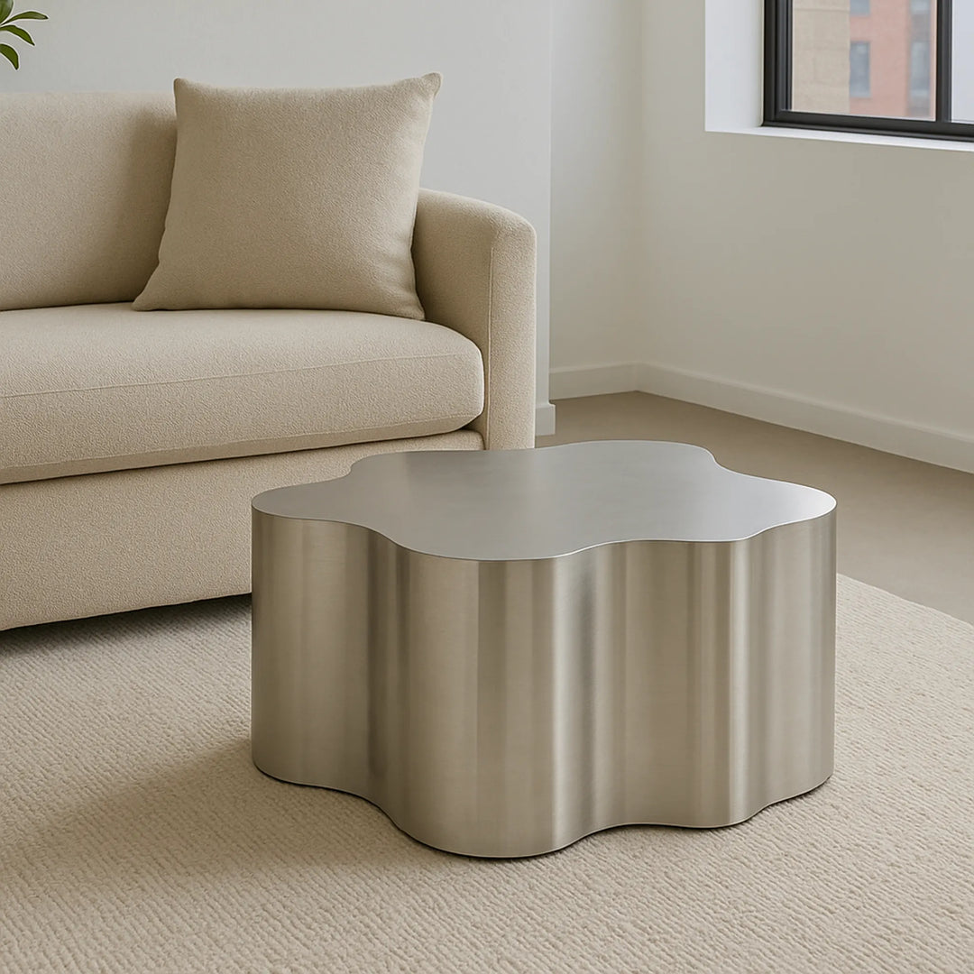The Genevive Stainless Steel Coffee Table (Medium) complements a contemporary couch, creating a polished living room look.