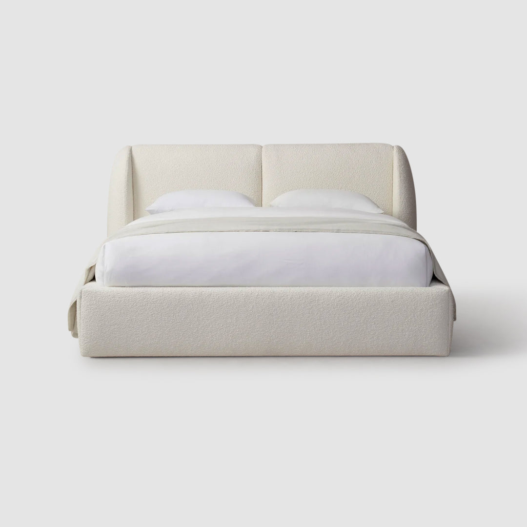 White platform bed with crisp white bedding on a white backdrop. luxury bedding