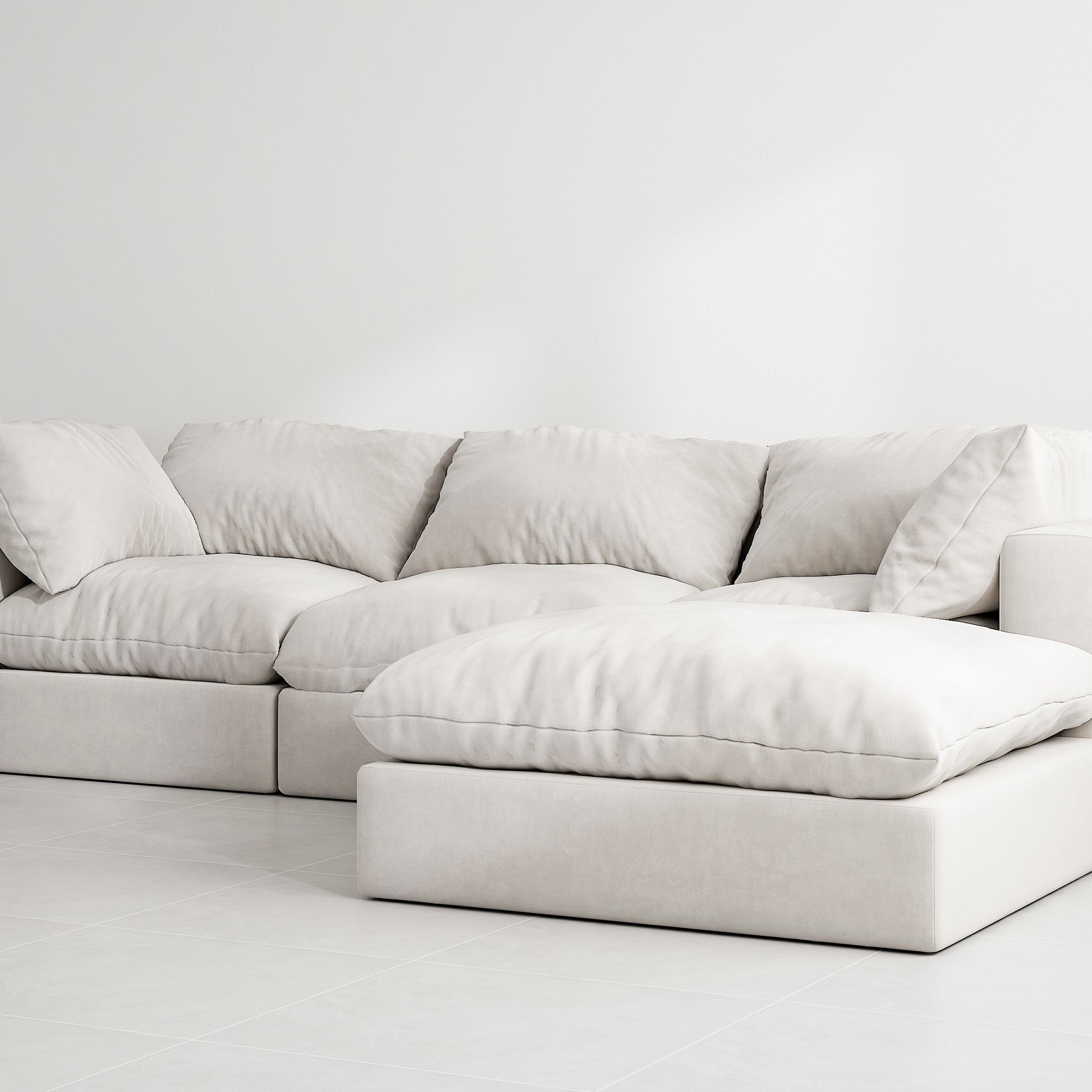 White sectional couch with detachable ottoman in a modern living room. The couch has soft cushions and a solid wood frame.