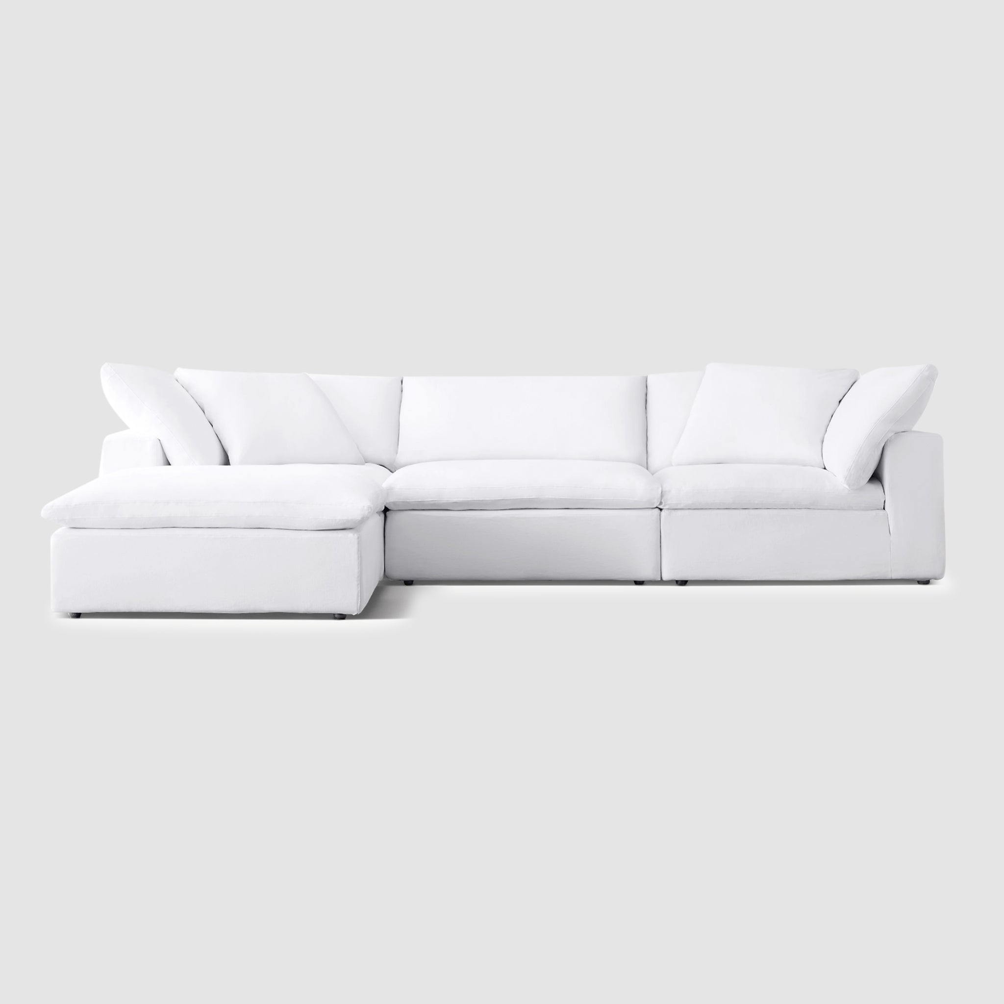 White sectional couch with detachable ottoman in a modern living room. The couch has soft, cloud-like cushions and a solid 4 Seater Premium Sofawood frame.