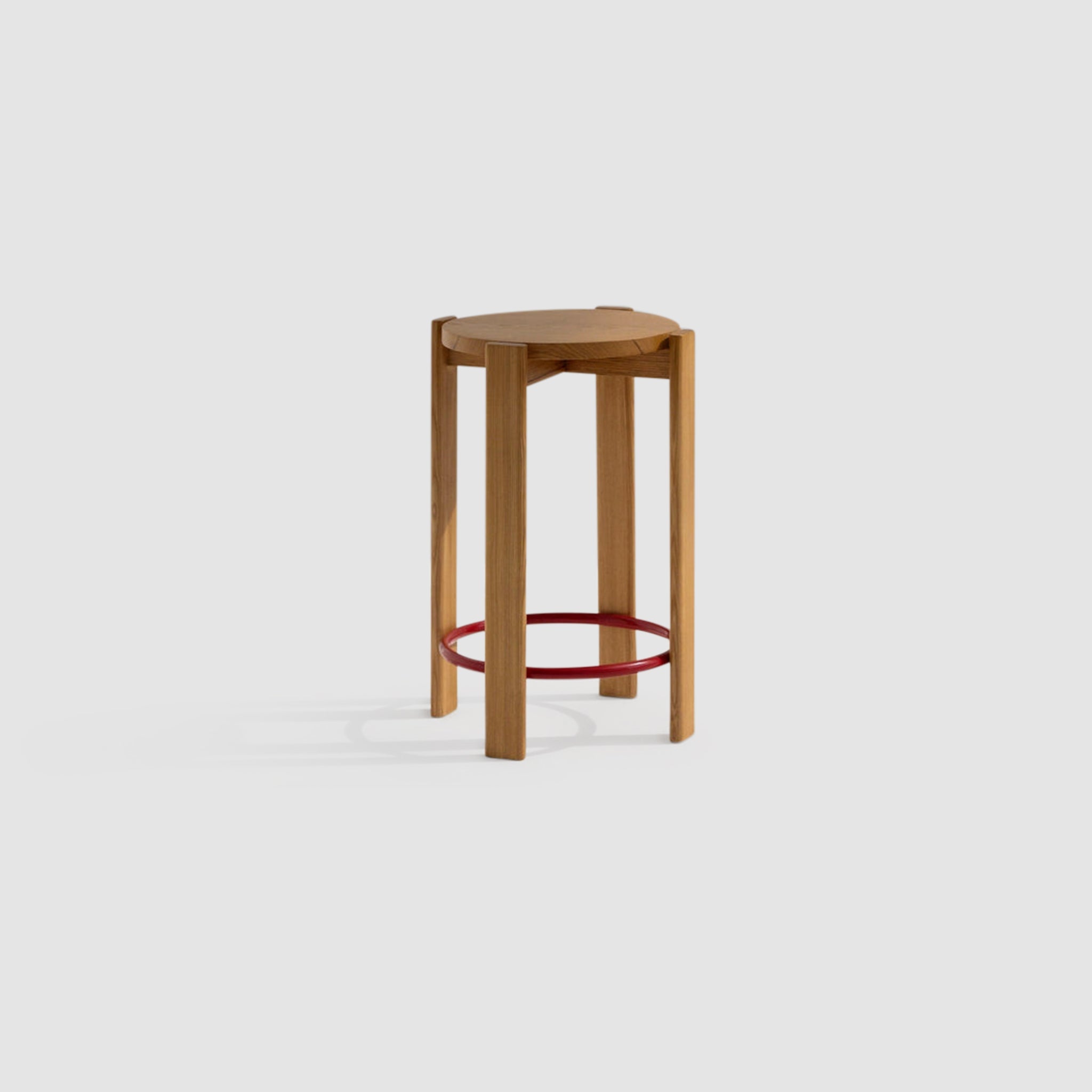 Wooden tall stool with a round seat and a red circular footrest on a white background