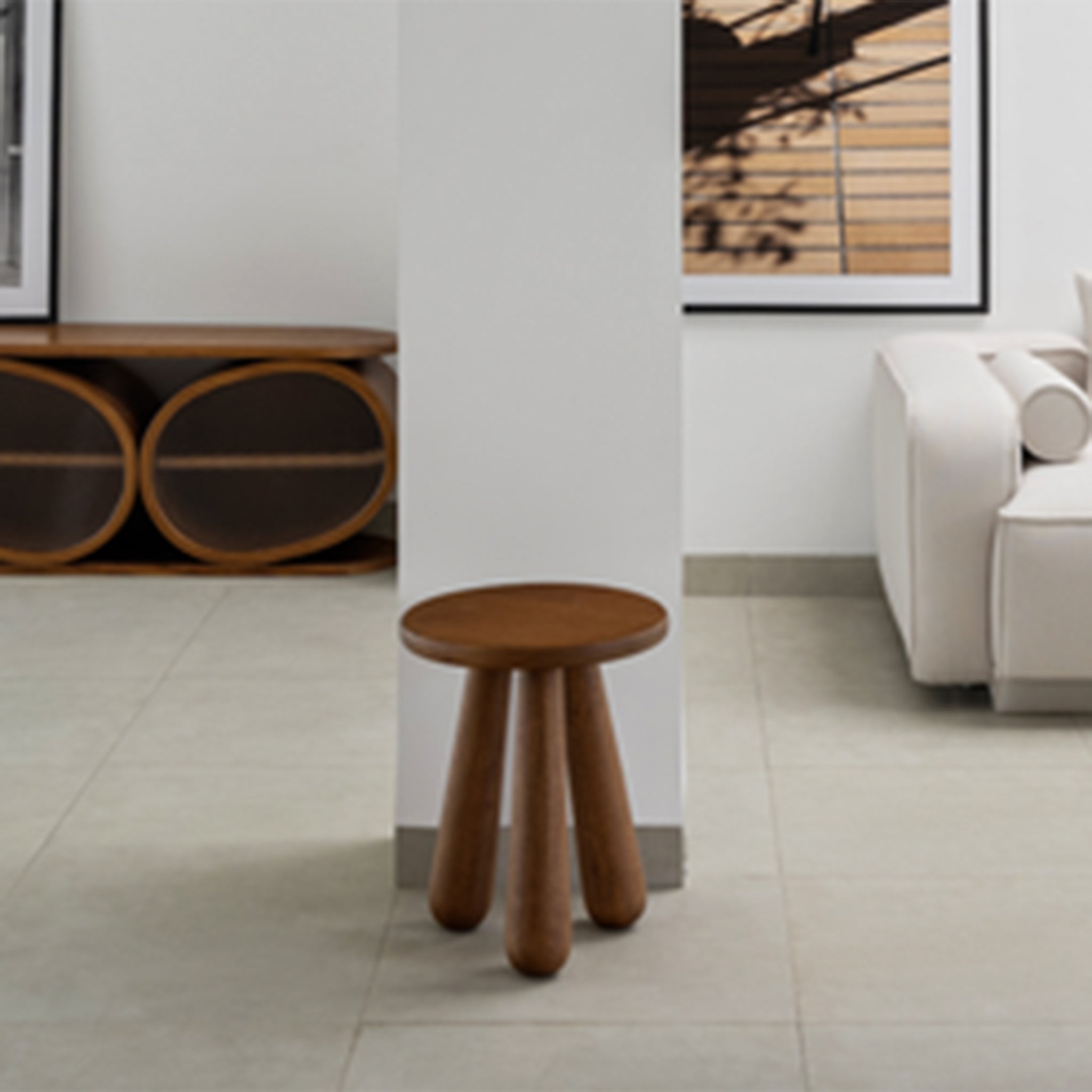 Brown wooden side table with chunky legs placed against a white column in a modern living room with minimalist decor