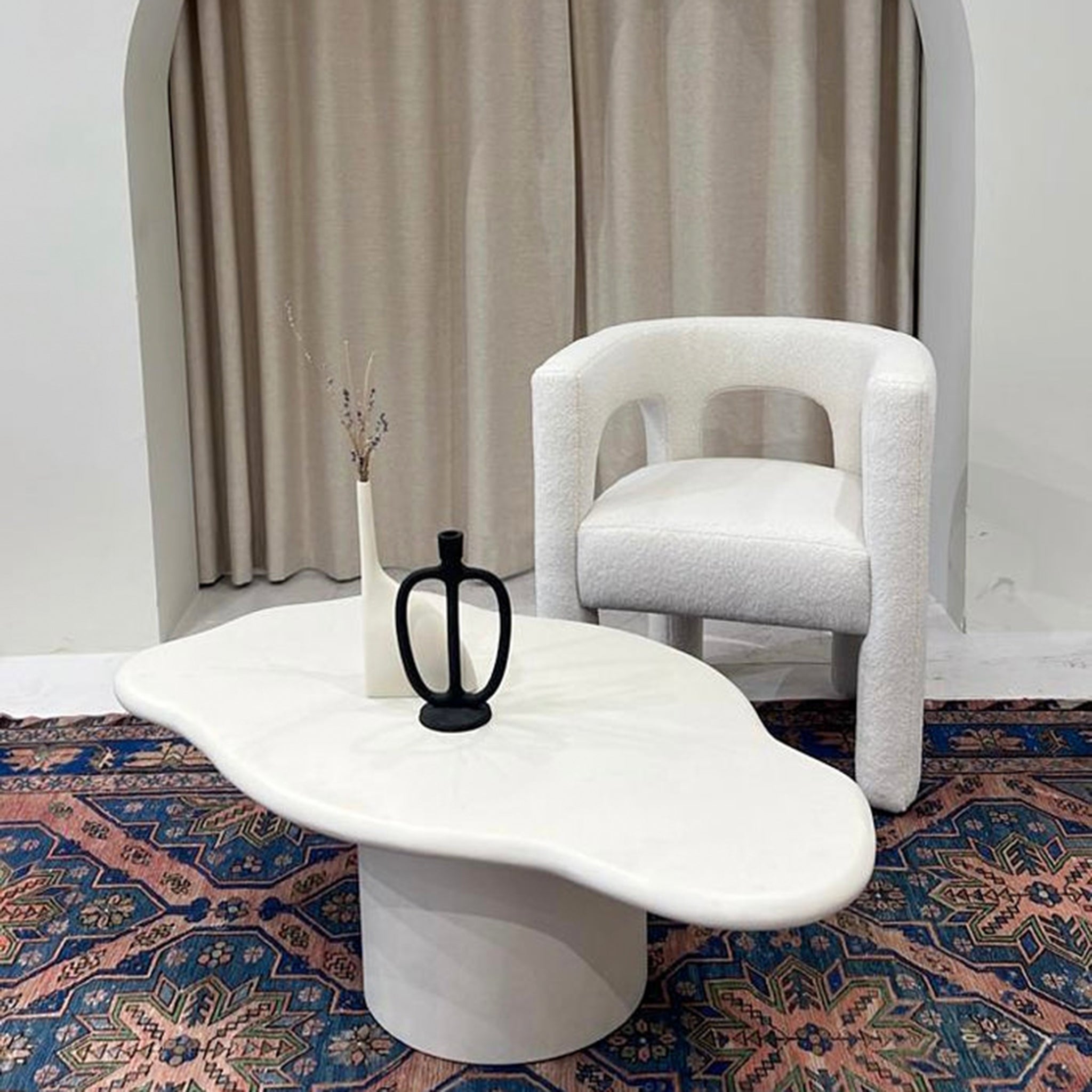 Stylish living room setup featuring The Celeste Accent Chair in white, paired with a uniquely shaped white coffee table and decorative vases on a patterned rug.accent chairs dubai