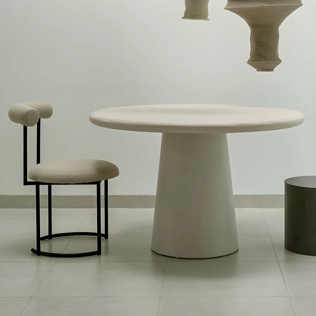 The Claudia round dining chair positioned around a modern dining table, enhancing a sophisticated dining room.