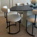 Load image into Gallery viewer, The Claudia round dining chair, featured in a stylish dining area with a sleek wooden table.
