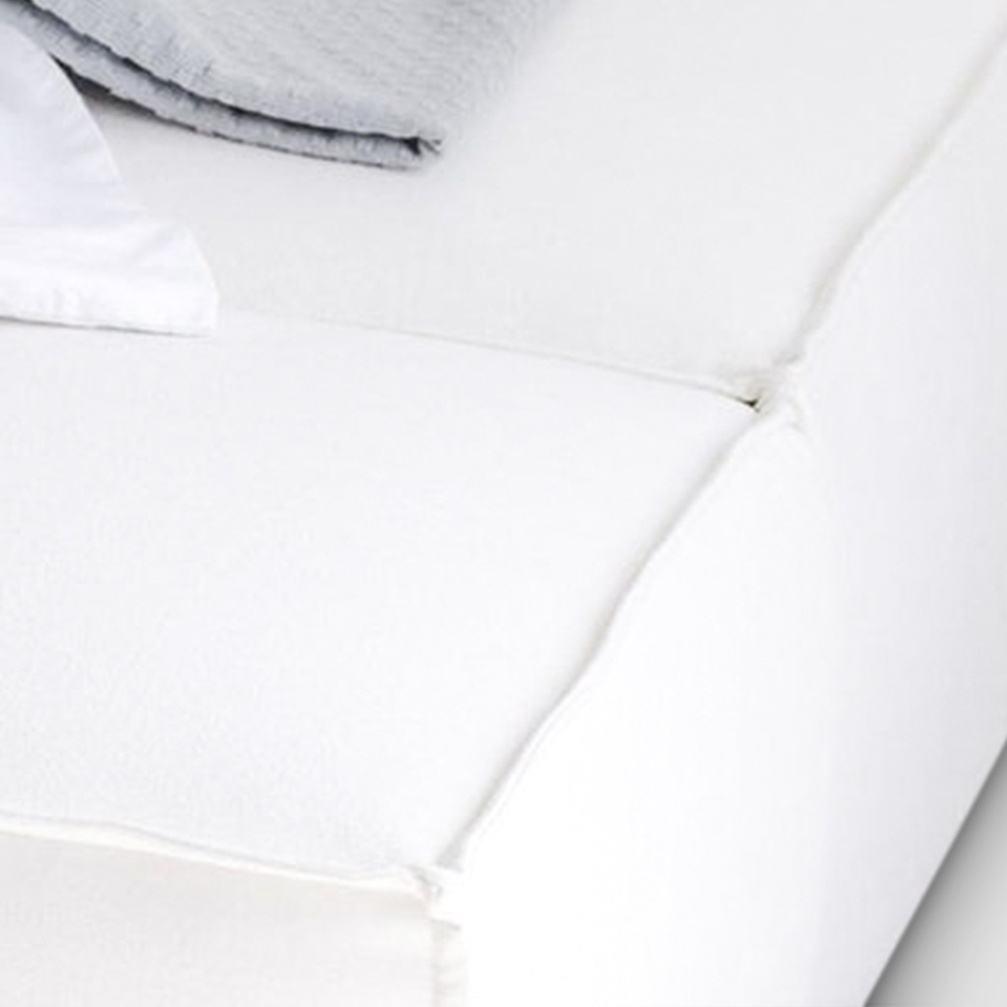 Close-up of plush white mattress with a gray blanket. Soft and inviting sleep surface.
