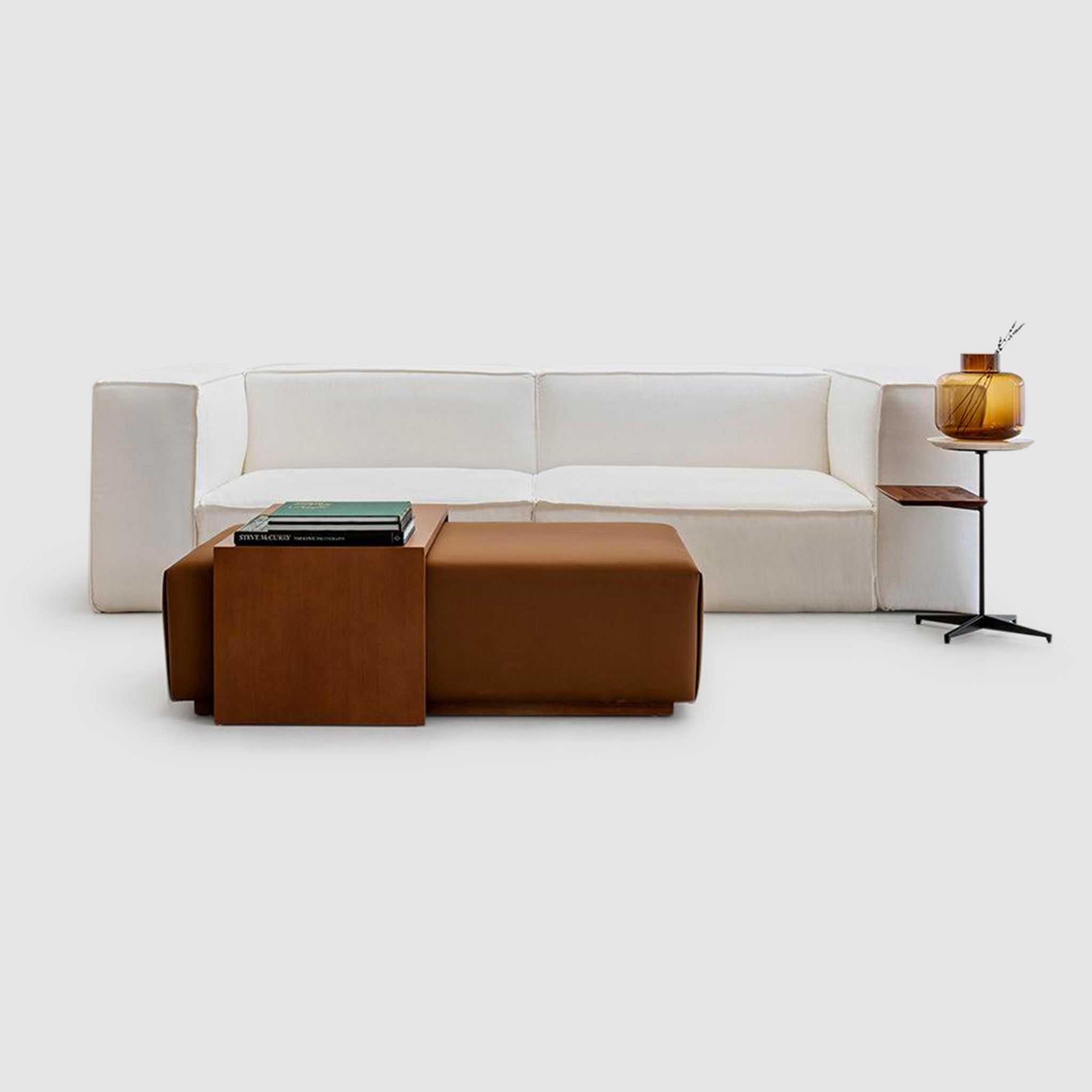 Relaxing living room setup with a white couch, brown ottoman, and side table for a comfortable and stylish space.