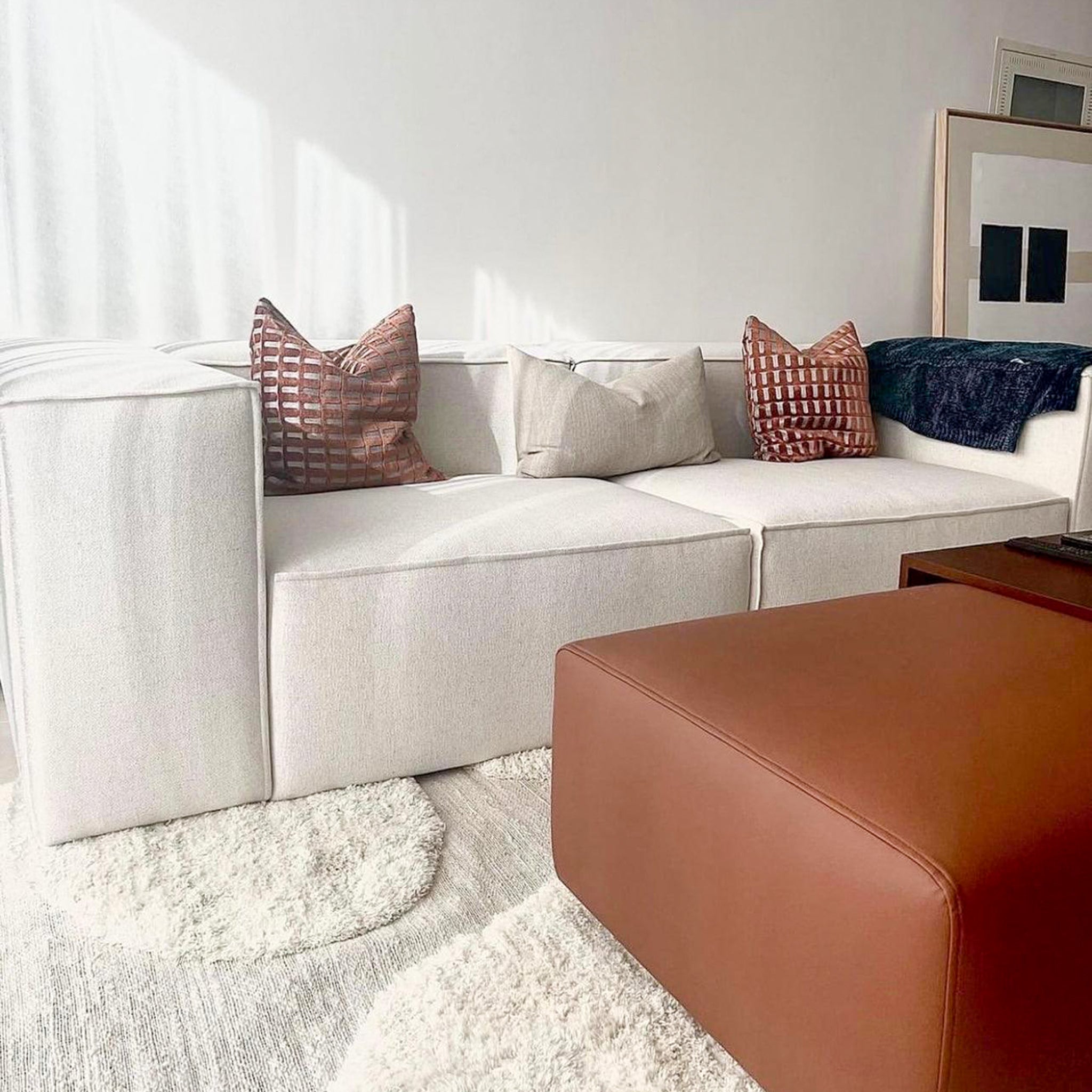 White couch with plush cushions and a brown ottoman for comfortable living room seating
