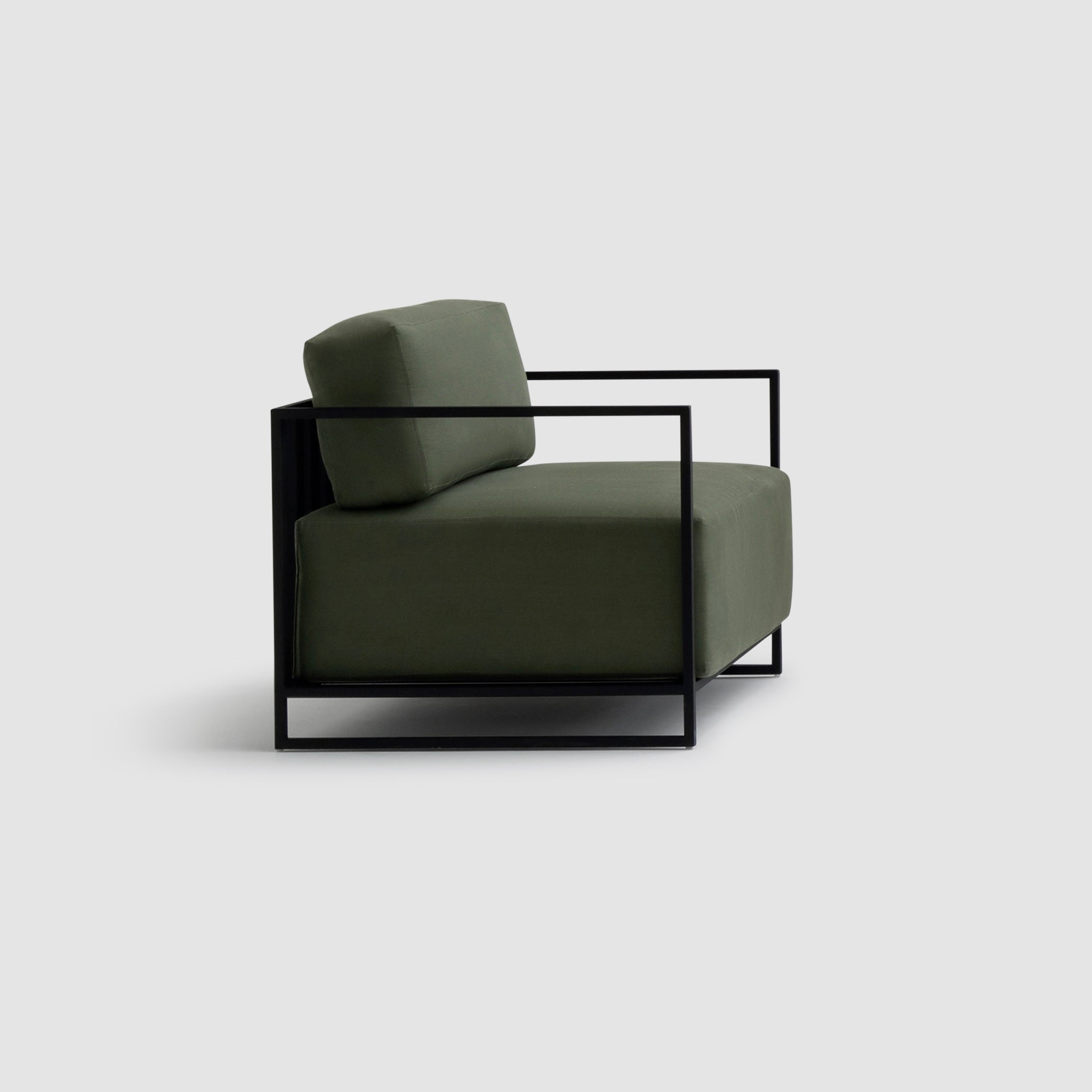 Side view of The Dexter Accent Chair featuring a sleek black metal frame and olive green cushions, showcasing its modern and minimalist design.