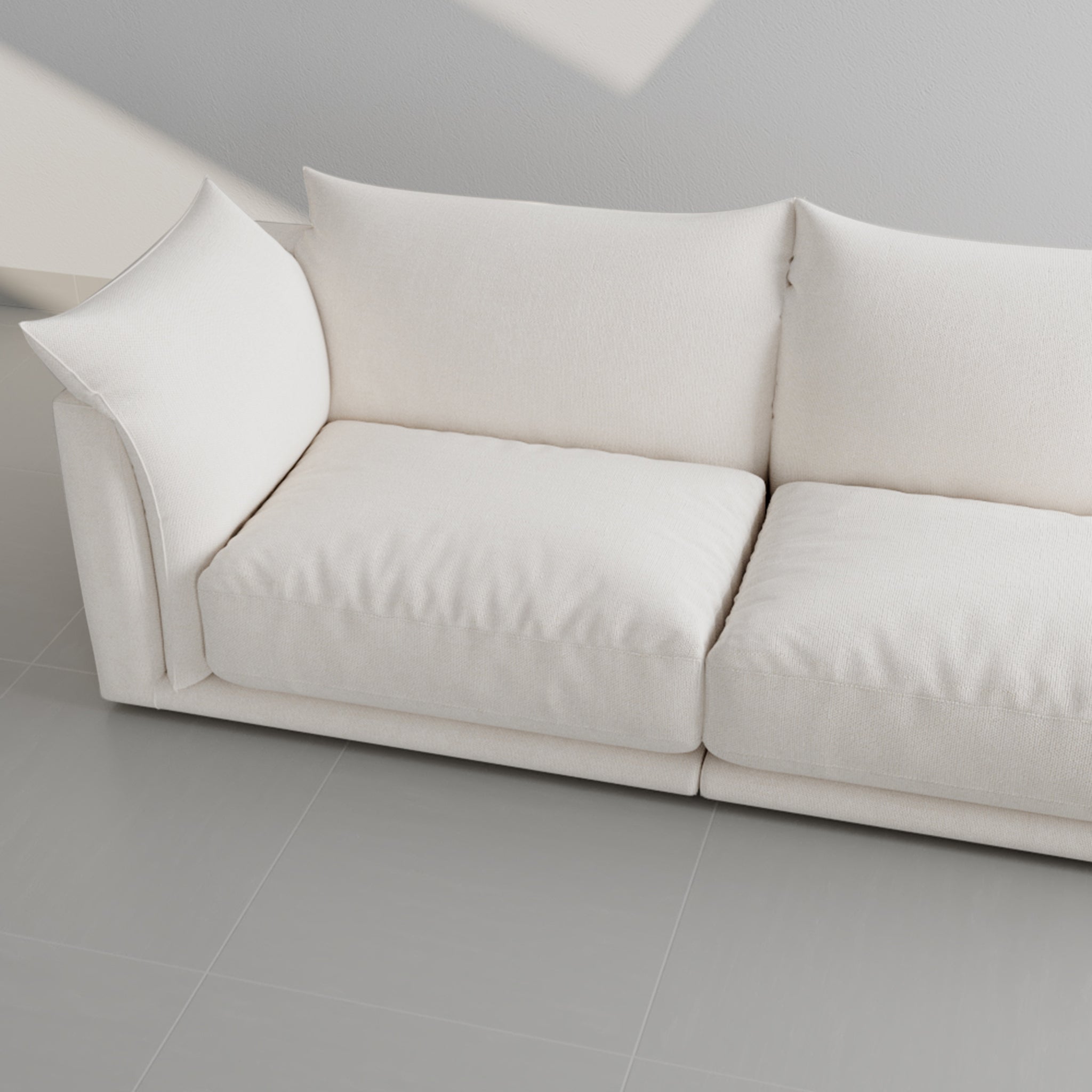 Top view of a modern white sofa with plush cushions in a minimalist living room with natural light.