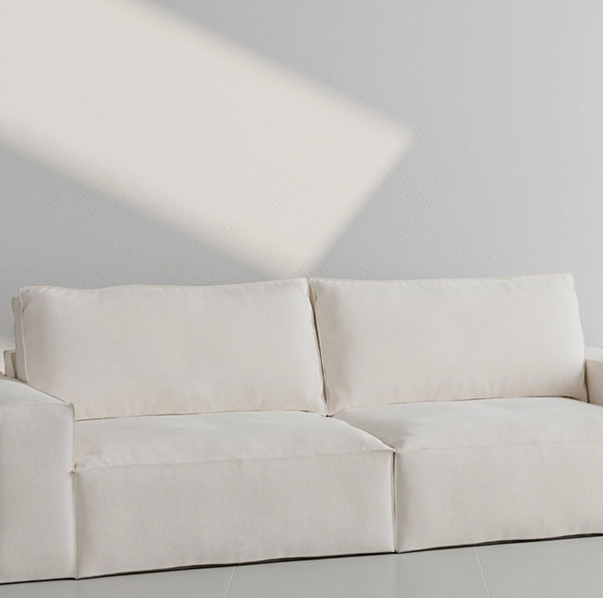 White three-seater sofa with plush cushions in a minimalistic room