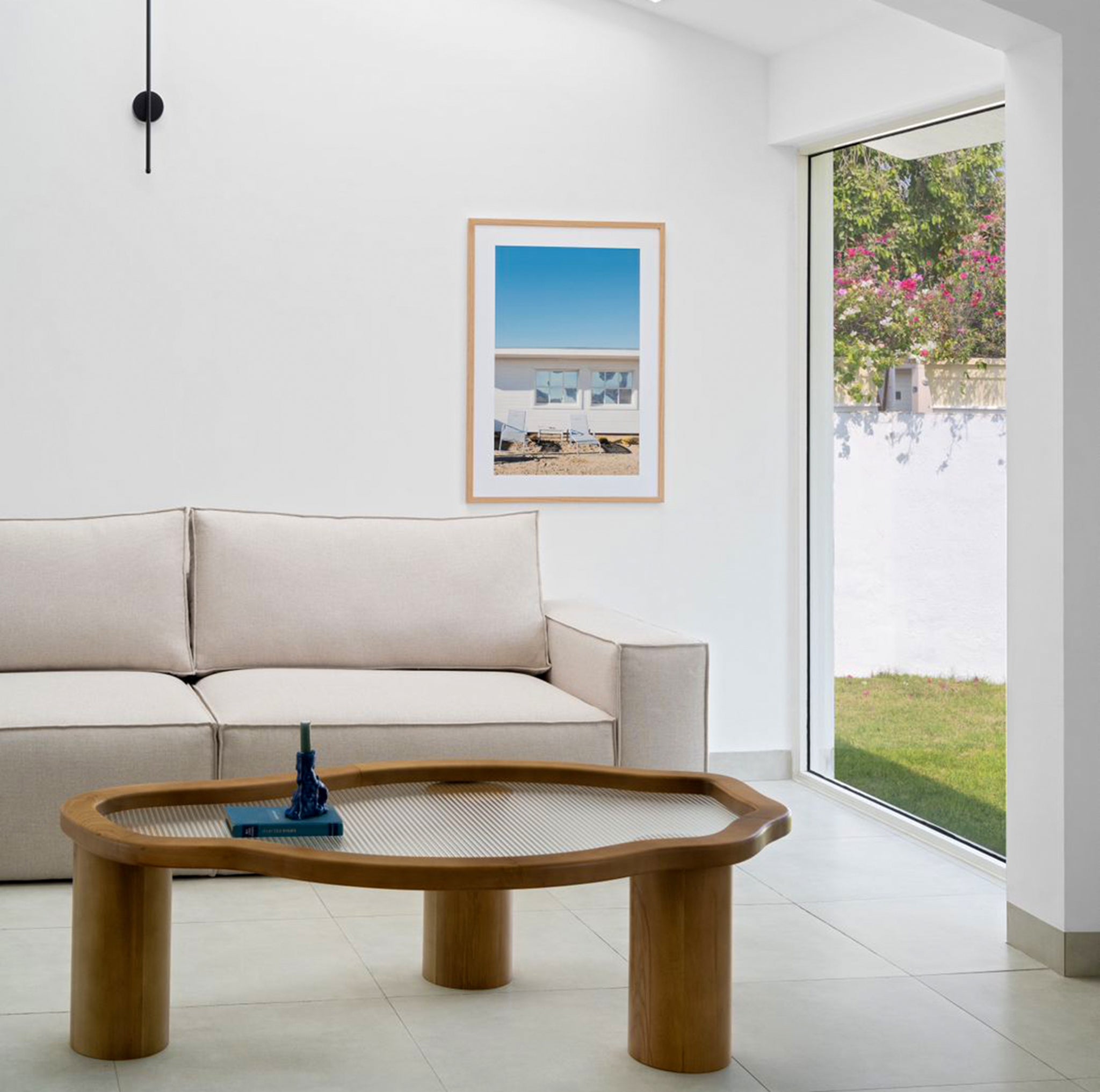 Living room featuring a white L-shaped couch, brown leather ottoman, and a wooden side table with a lamp for a warm and inviting space - buy sofa set Dubai