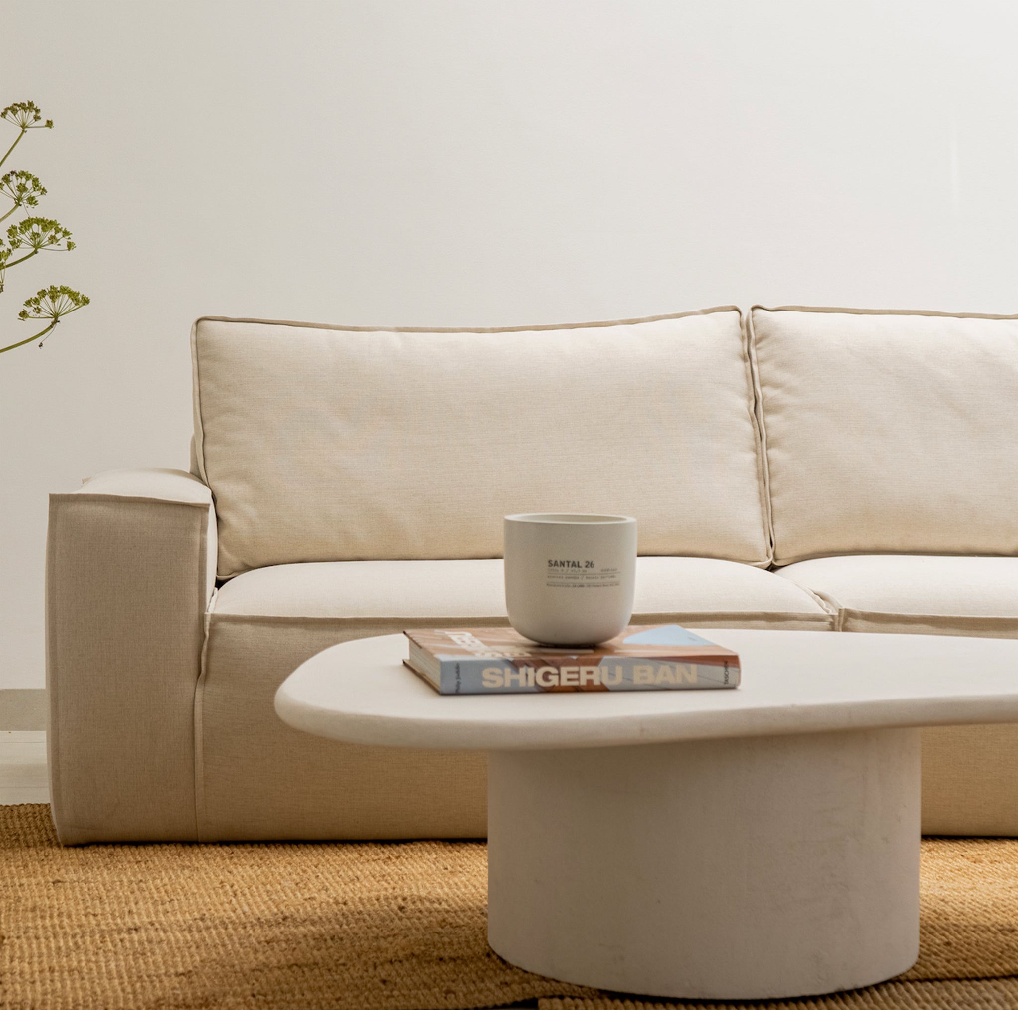 Living room featuring a plush white corner sofa, rich brown leather ottoman, and a decorative lamp on a wooden accent table - buy sofa set Dubai