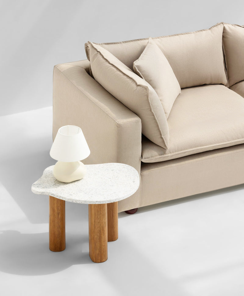 Beige sofa with plush cushions beside a modern, white stone coffee table with wooden legs, creating a cozy and stylish living space. buy luxurious sofa