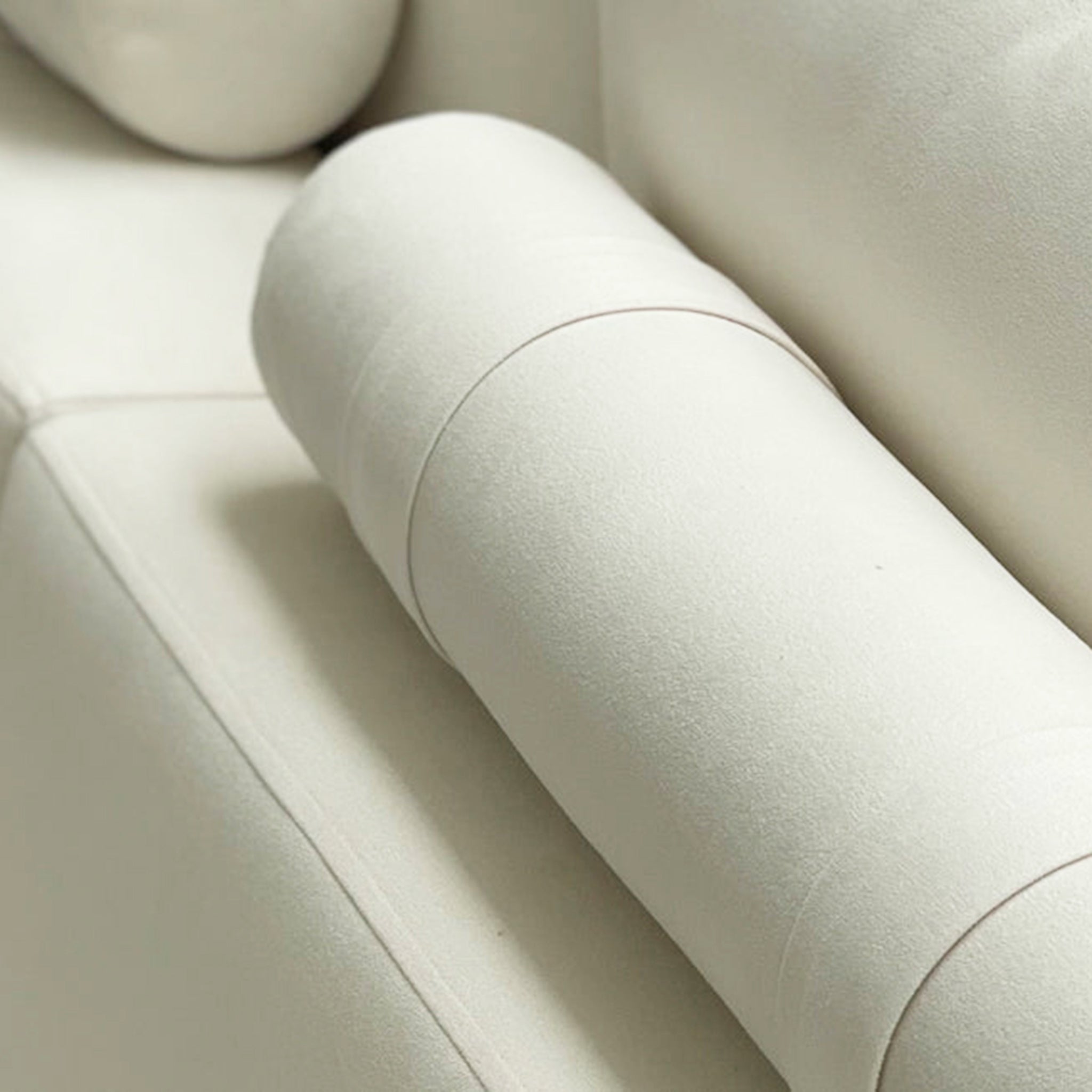 Close-up view of a plush white sofa cushion, showcasing the fine stitching and luxurious fabric, perfect for highlighting the attention to detail in modern furniture design.