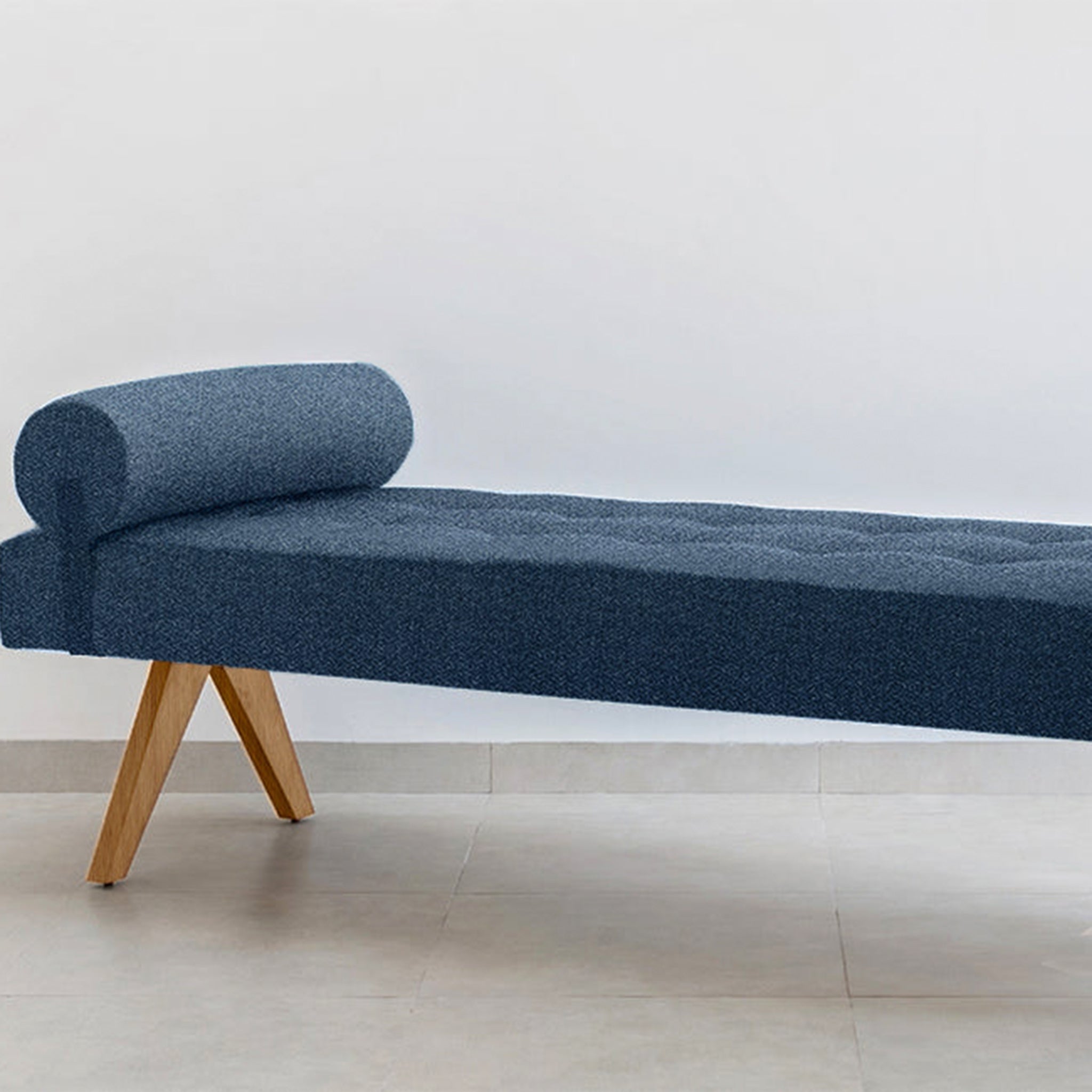 The Jack Daybed with deep blue upholstery and wooden legs