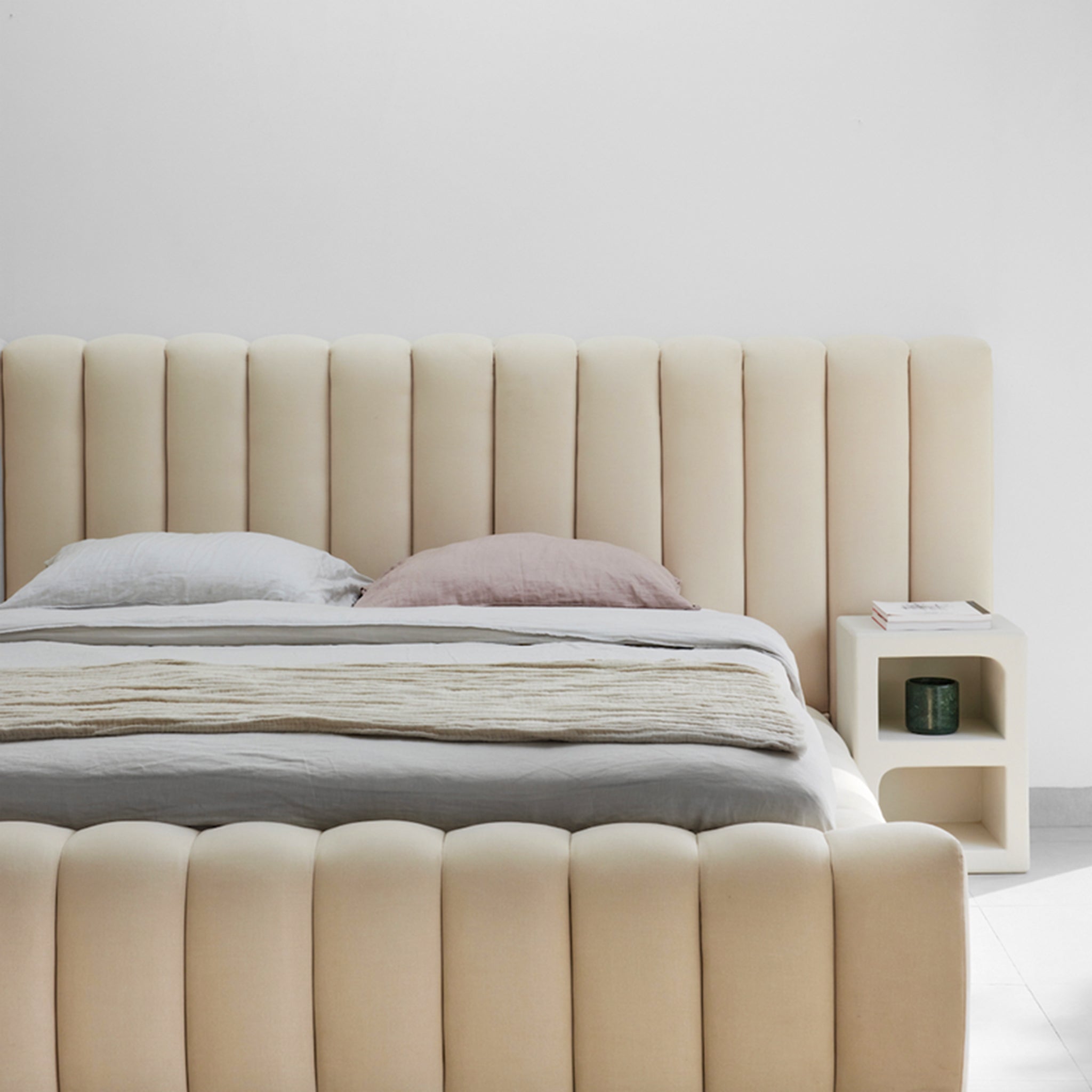 light gray king-size platform bed with a curved, button-tufted headboard and a white nightstand. The Jemima Bed by Klettkic creates a sophisticated and inviting bedroom retreat.