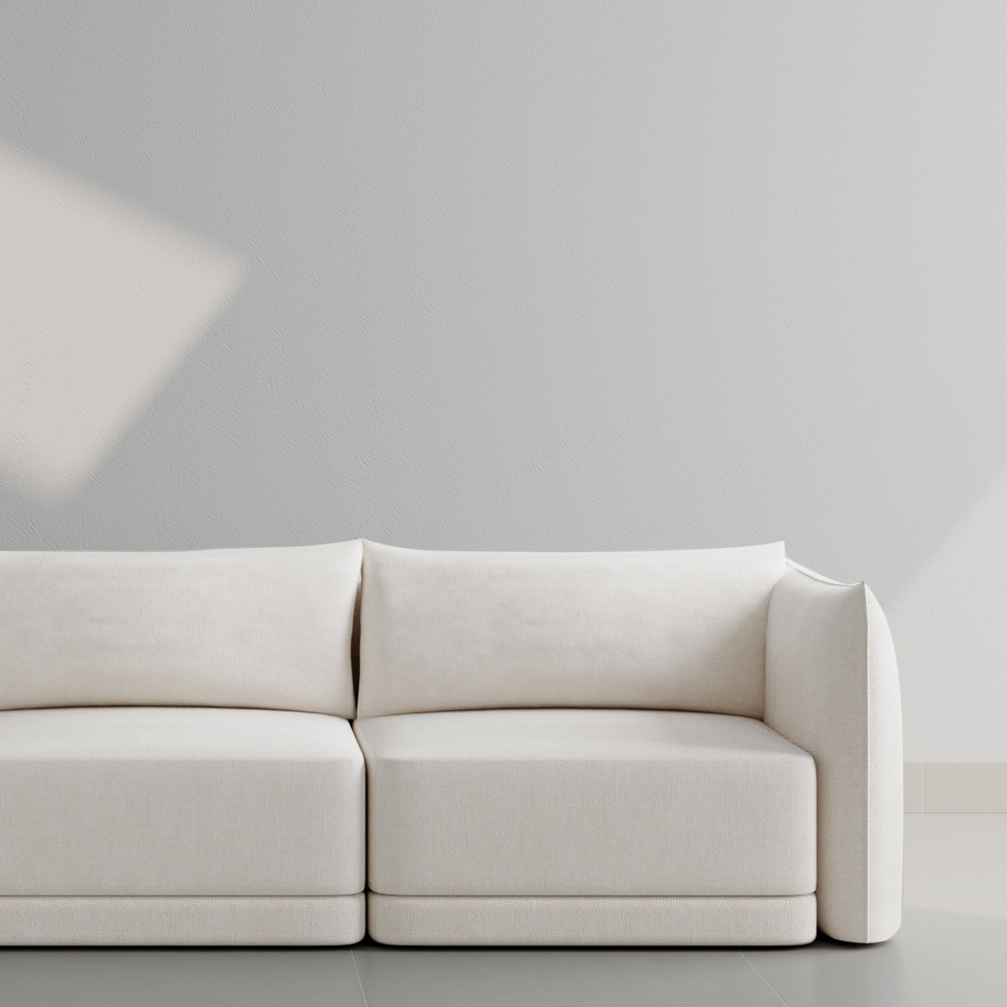 Minimalist white sofa against a light gray wall, showcasing modern design and clean lines for a contemporary living space.