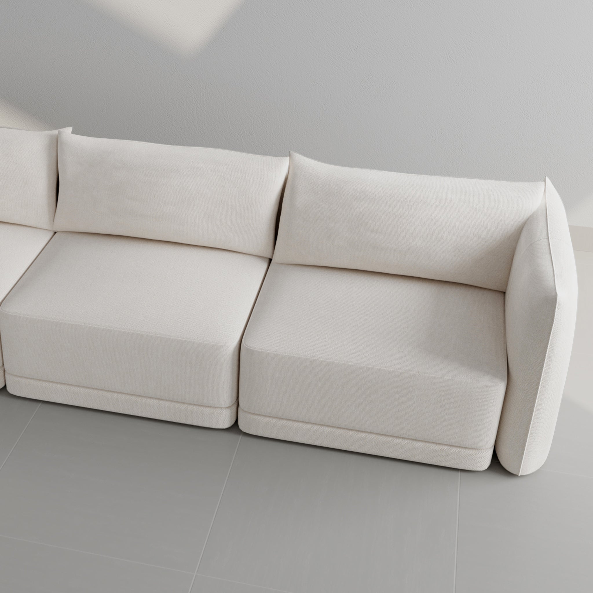 Top view of a modern white sectional sofa placed against a gray tiled floor, highlighting its spacious seating and contemporary design.