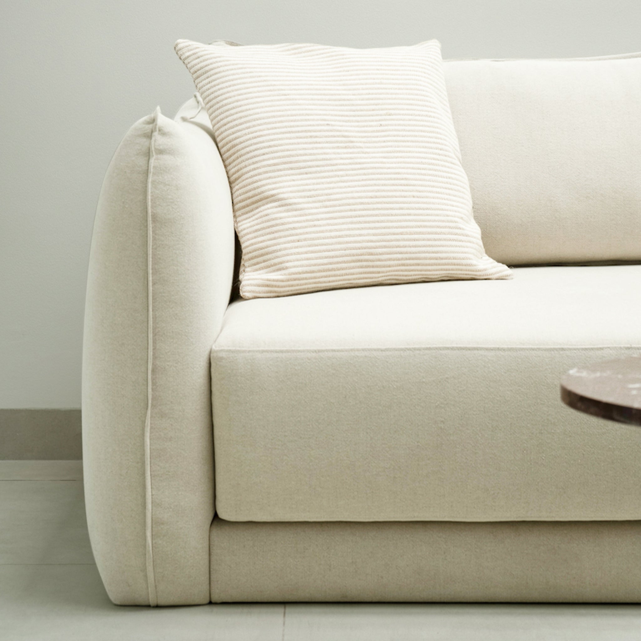 Close-up of a 0ff-white modern sofa with a striped cushion, emphasizing clean lines and minimalistic design.
