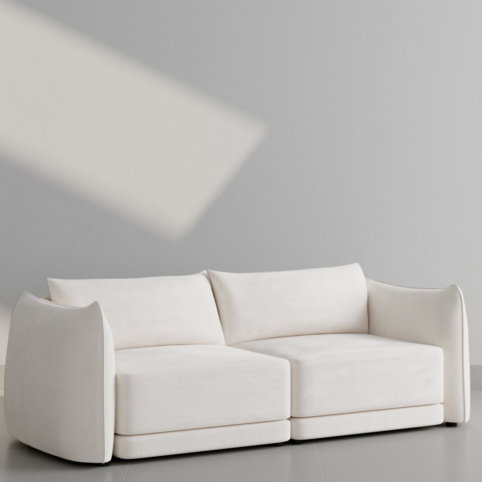 Modern white sofa with curved armrests against a light gray wall, featuring soft cushions and minimalist design. modern 2 seater sofa