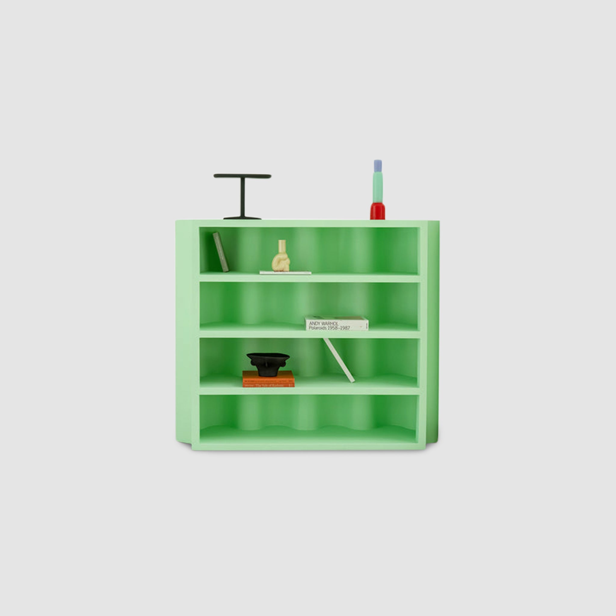 A modern green bookcase with multiple shelves, featuring a minimalist design and various decorative items placed on it.