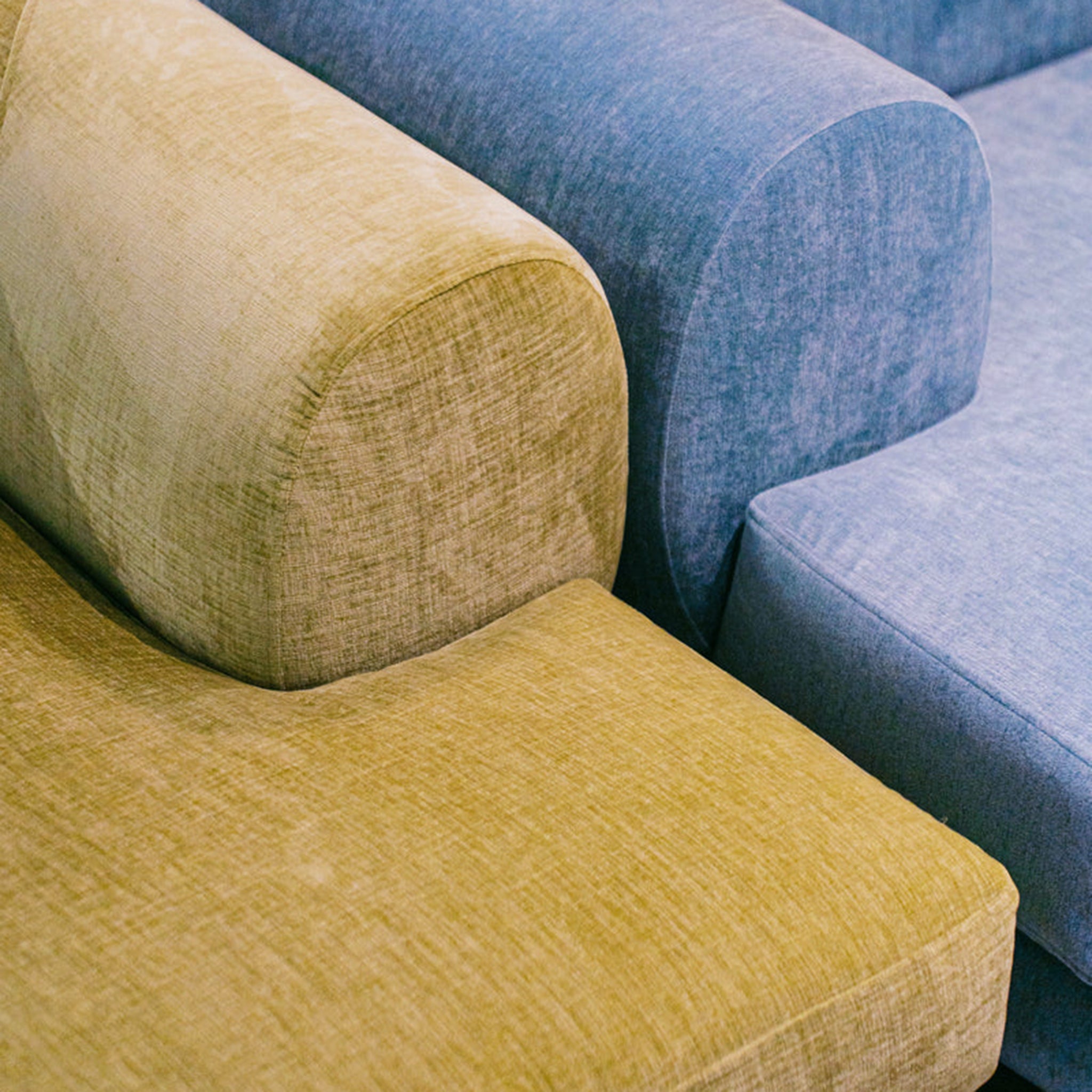 "Close-up view of The Lewis Low Lounger Accent Chairs in green and blue upholstery, highlighting their soft fabric texture and rounded armrest design."