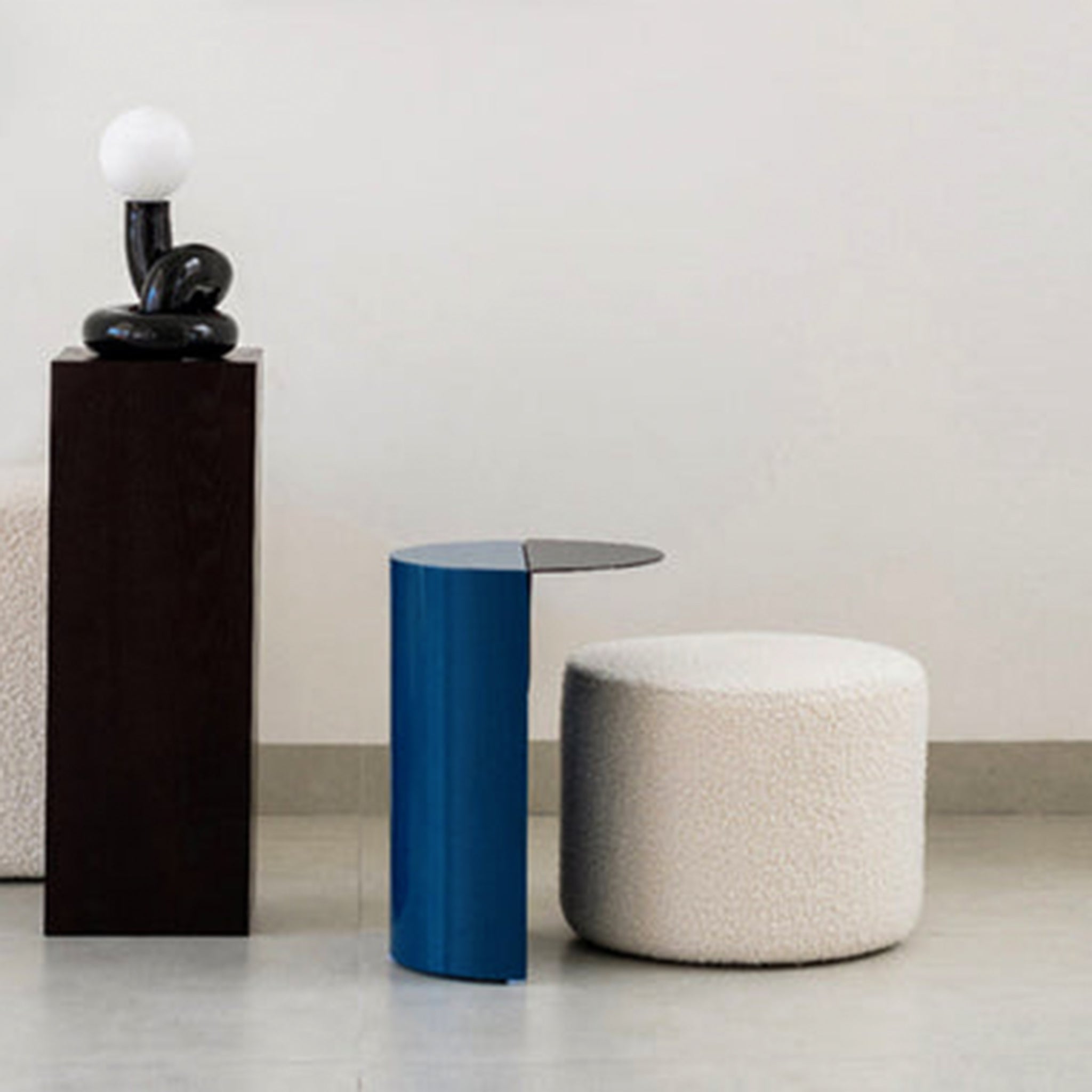 White ottoman and blue side table with a lamp on a white background