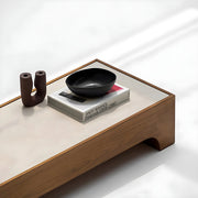 The Noah Low Coffee Table set against a grey backdrop, highlighting its rich wood grain and marble accents—ideal for modern living rooms.