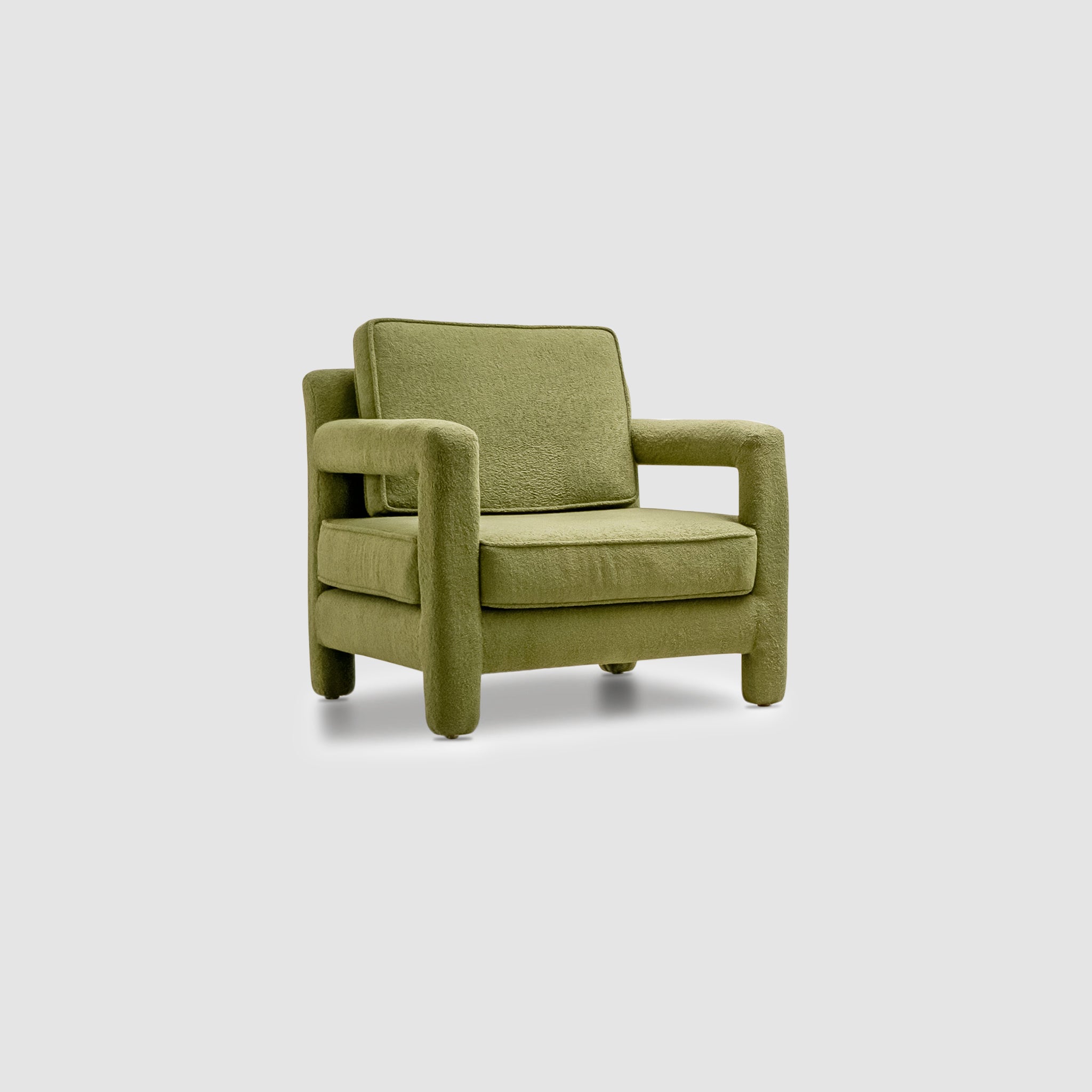 Angled view of The Parsons Accent Chair featuring soft green upholstery, plush cushioning, and rounded armrests, set against a plain background.
