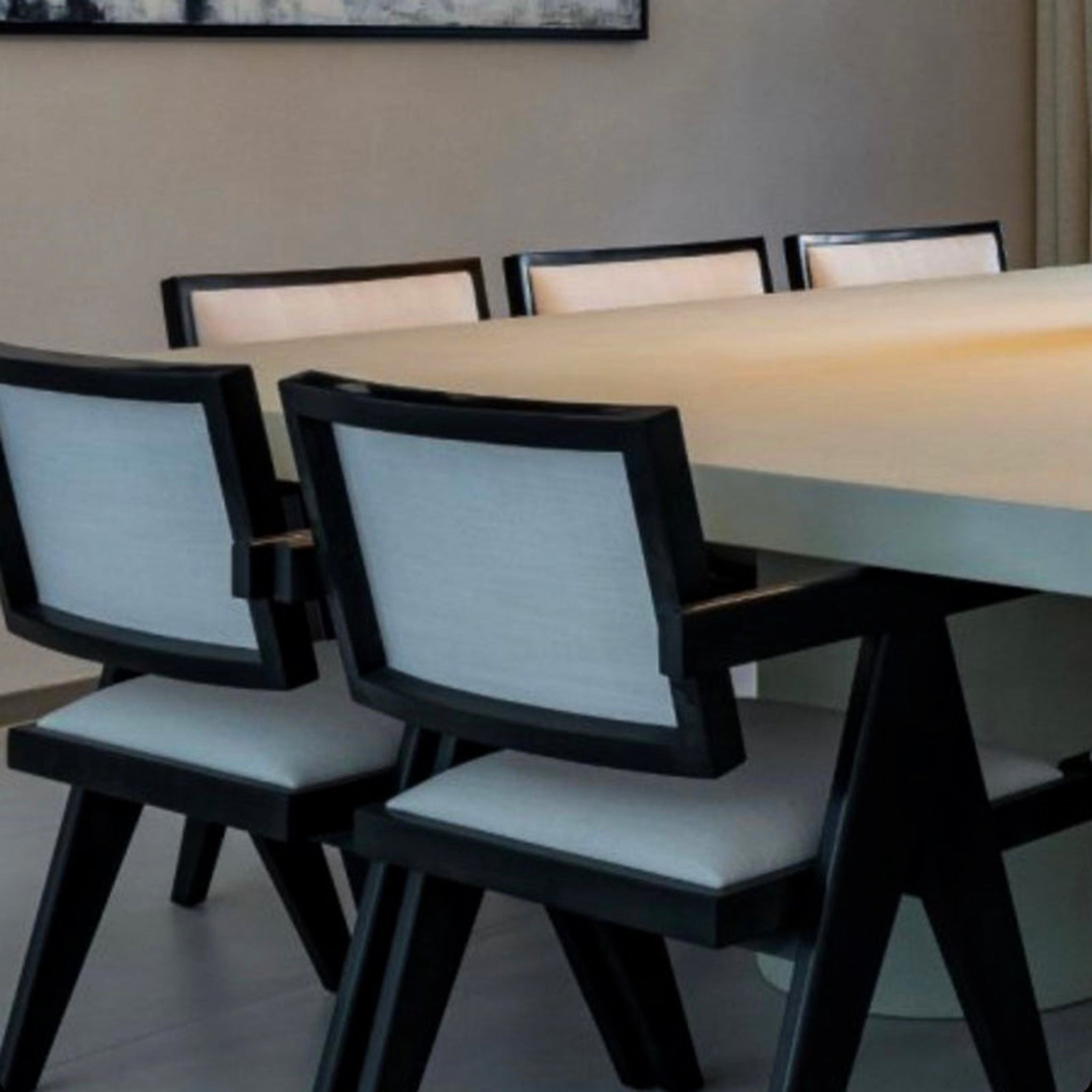 "The Pierre Dining Chair featuring sleek wooden construction and light fabric cushions."