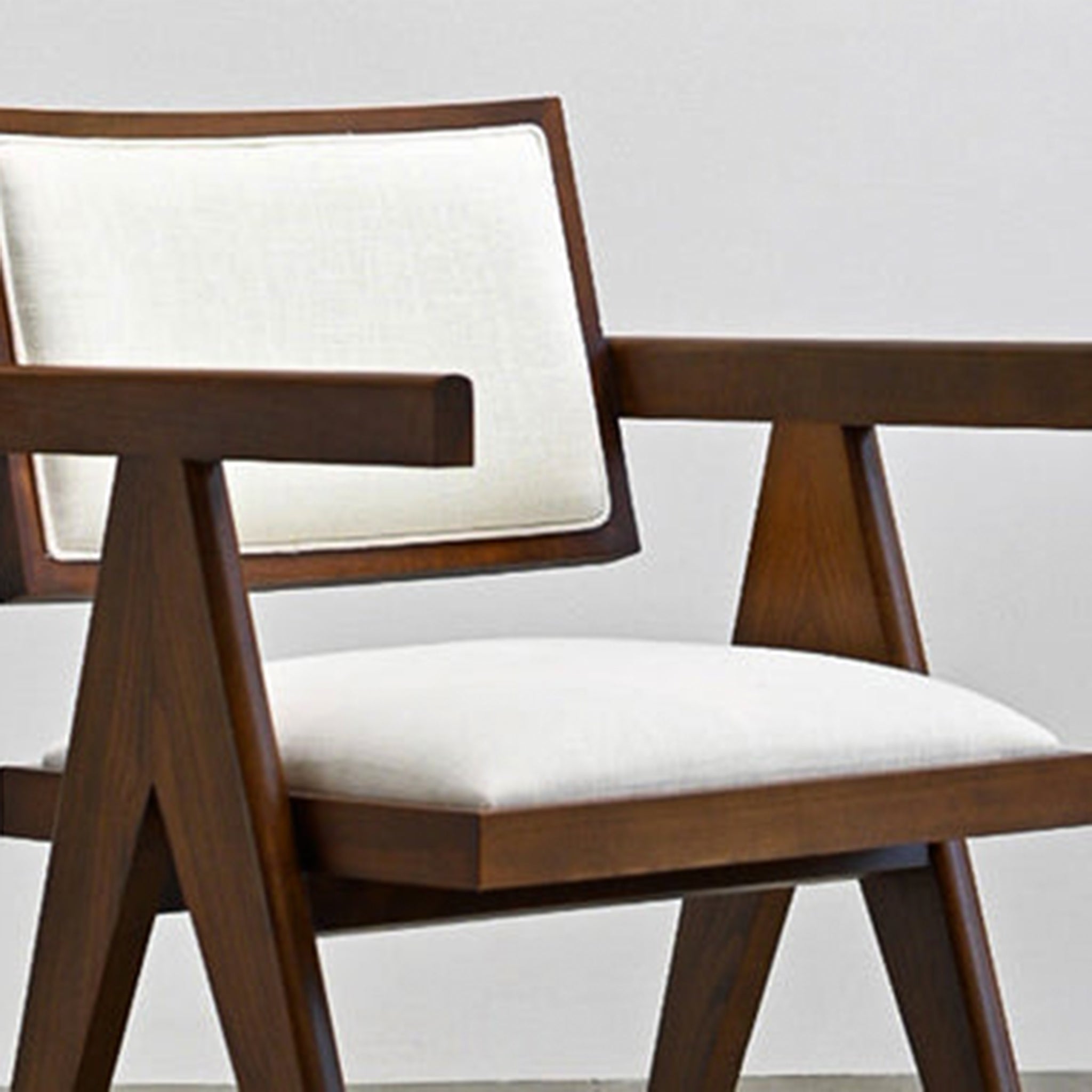 "Elegant side profile of The Pierre Dining Chair with light fabric cushions."