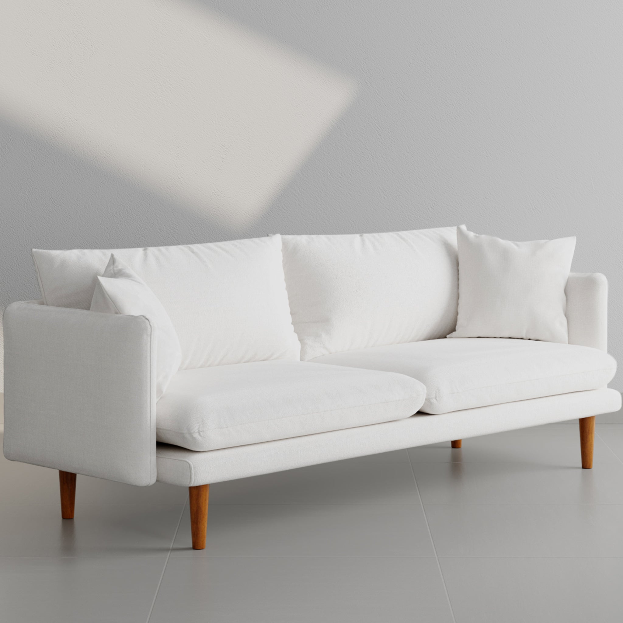 Angled view of a stylish white sofa with plush cushions and wooden legs, perfect for a contemporary living space.
