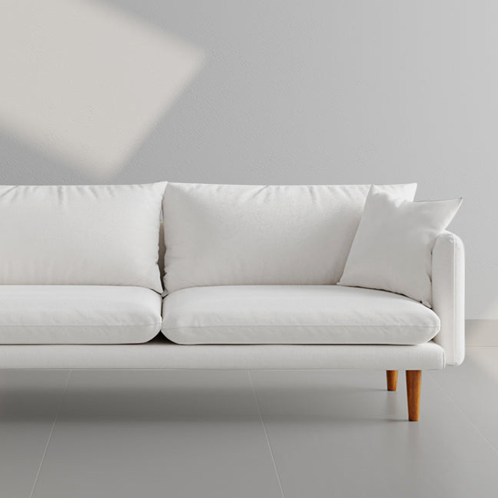 Modern white sofa with wooden legs and cozy cushions, perfect for a minimalist living room setup.
