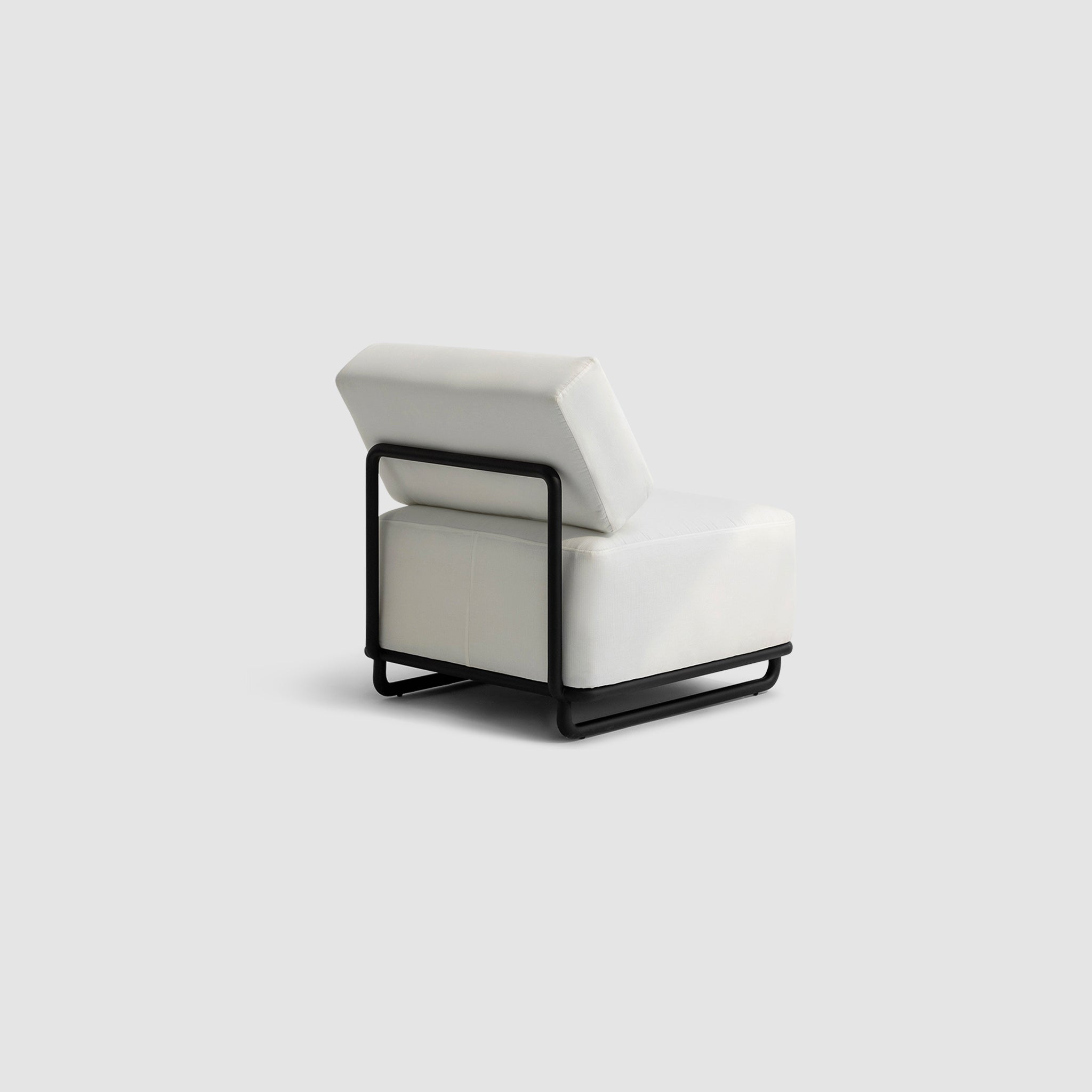 "Angled rear view of The Trevor Outdoor Modular Accent Chair featuring white cushions and a sleek black metal frame, set against a plain background."
