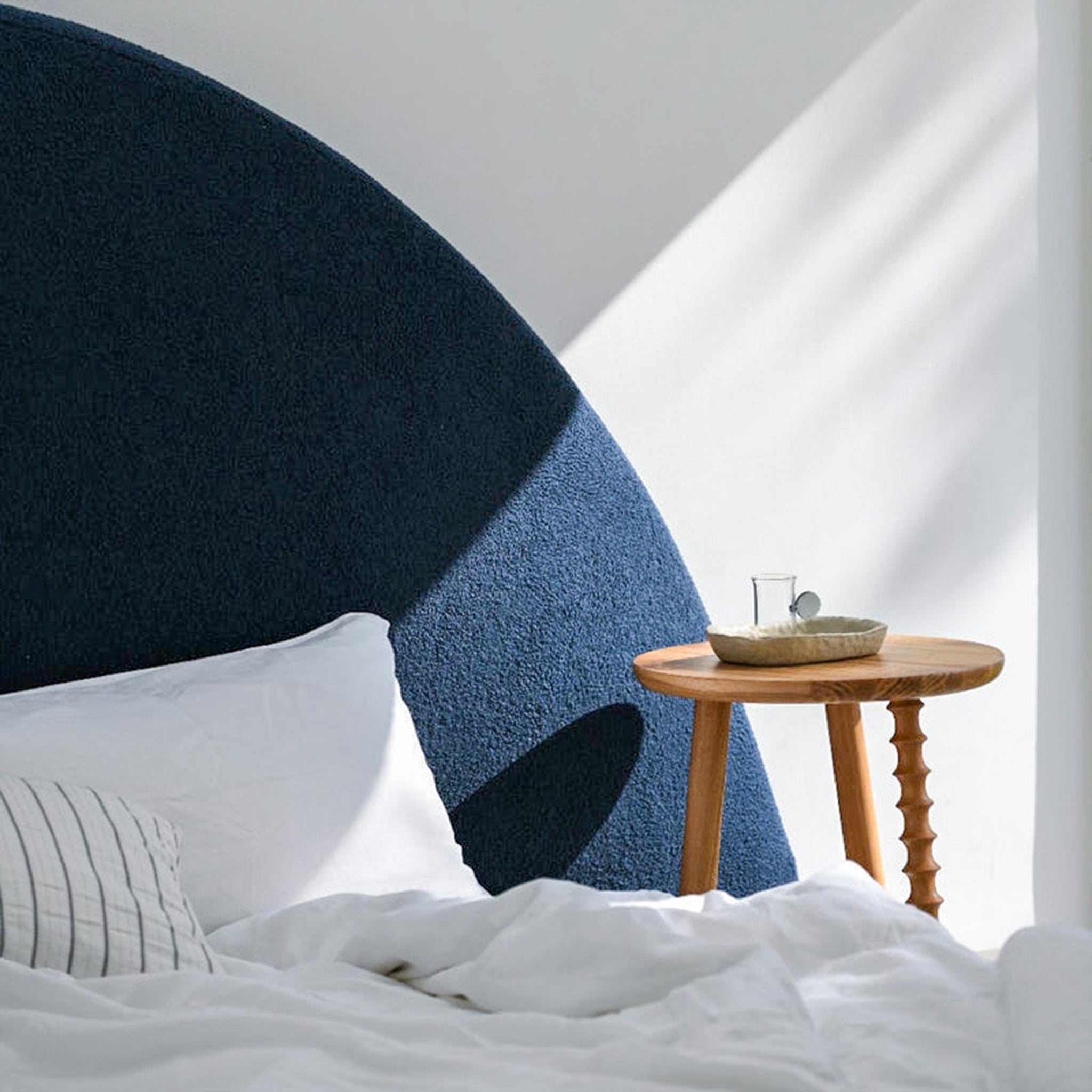 Blue upholstered king size bed with a large semi-circular headboard and a low profile frame