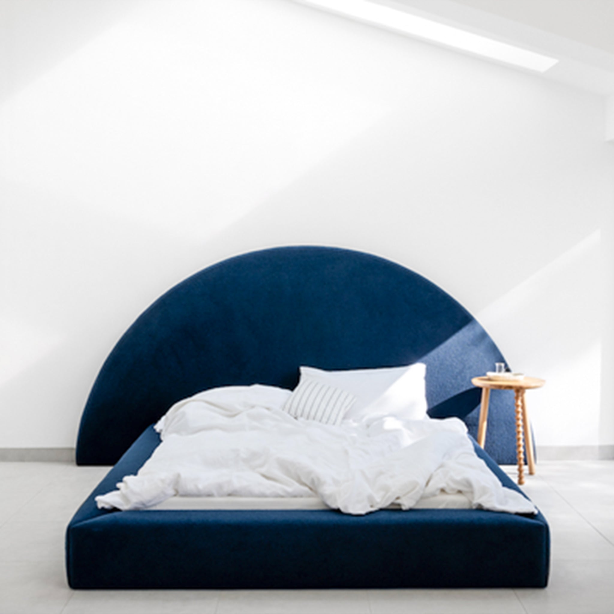 Blue upholstered bed with a large semi-circular headboard and a low profile frame. This luxurious bed is a stylish addition to any bedroom.