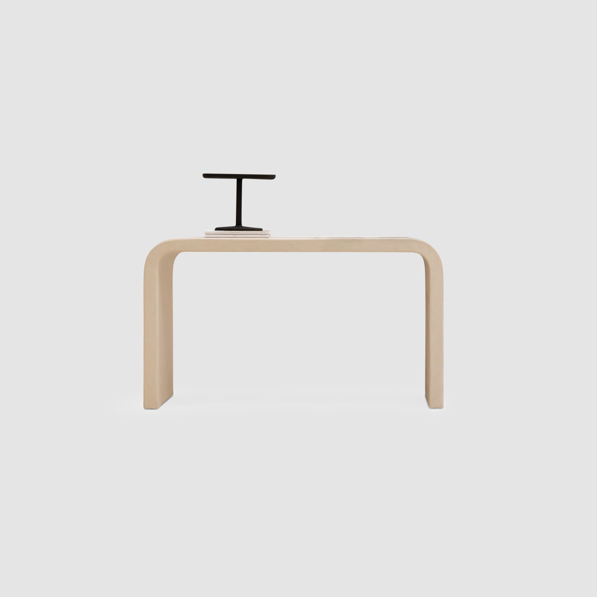 Modern minimalist console table with a sleek, curved design and a black desk accessory.