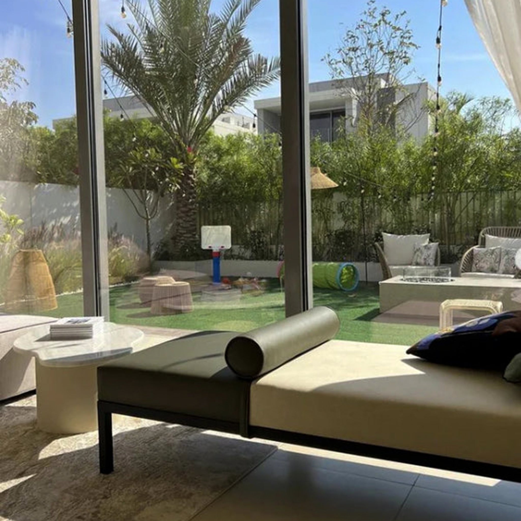 The Rodman Day Bed positioned by a large window with a view of a lush garden, showcasing its minimalist design with a Vegan Leather bolster cushion.