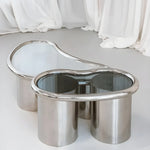 Load image into Gallery viewer, Close-up of The Willow Chrome Coffee Table With Small Gestures showcases its polished chrome legs and clear glass top.
