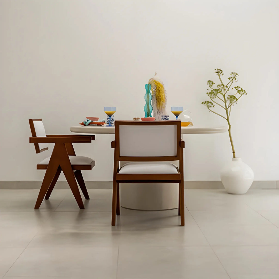 Round dining table with a microplaster finish, paired with chic chairs in a vibrant dining space.