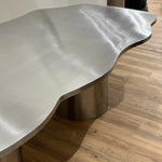 Load image into Gallery viewer, The Victoria steel dining table with a shiny stainless steel top, creating a statement in a contemporary dining room.
