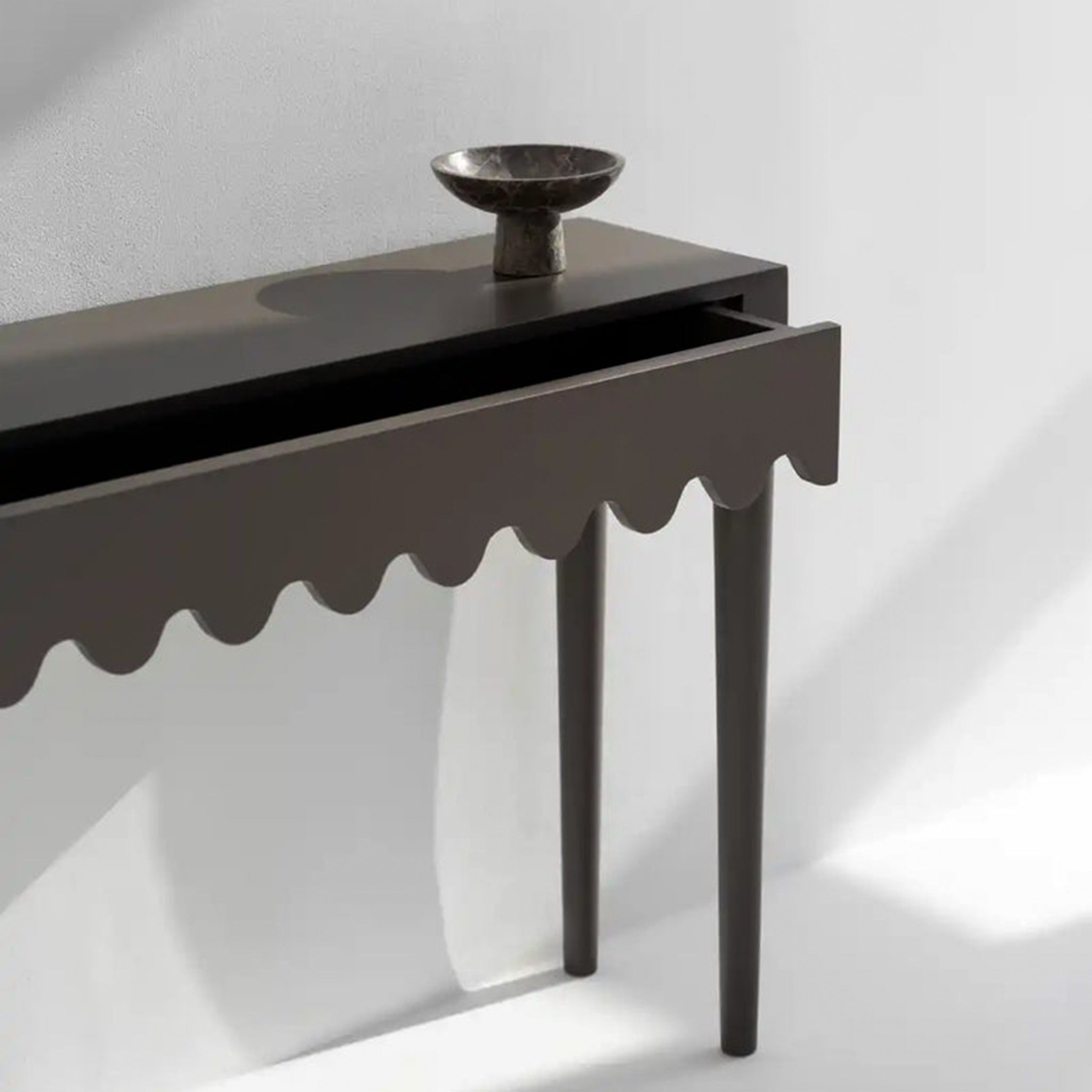 "Elegant black console table featuring a unique scalloped drawer for storage."